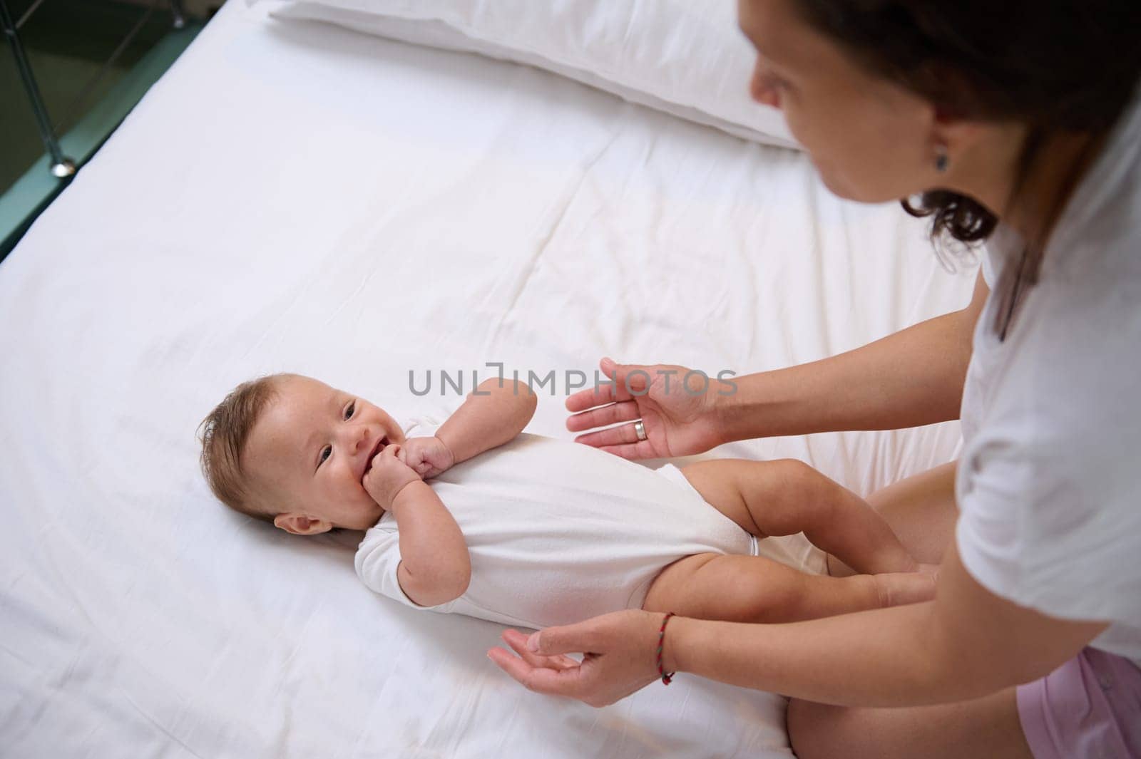 Adorable Caucasian baby boy laughing and smiling looking at his mom cuddling him. Babyhood and infancy. Maternity. Motherhood and baby care concept