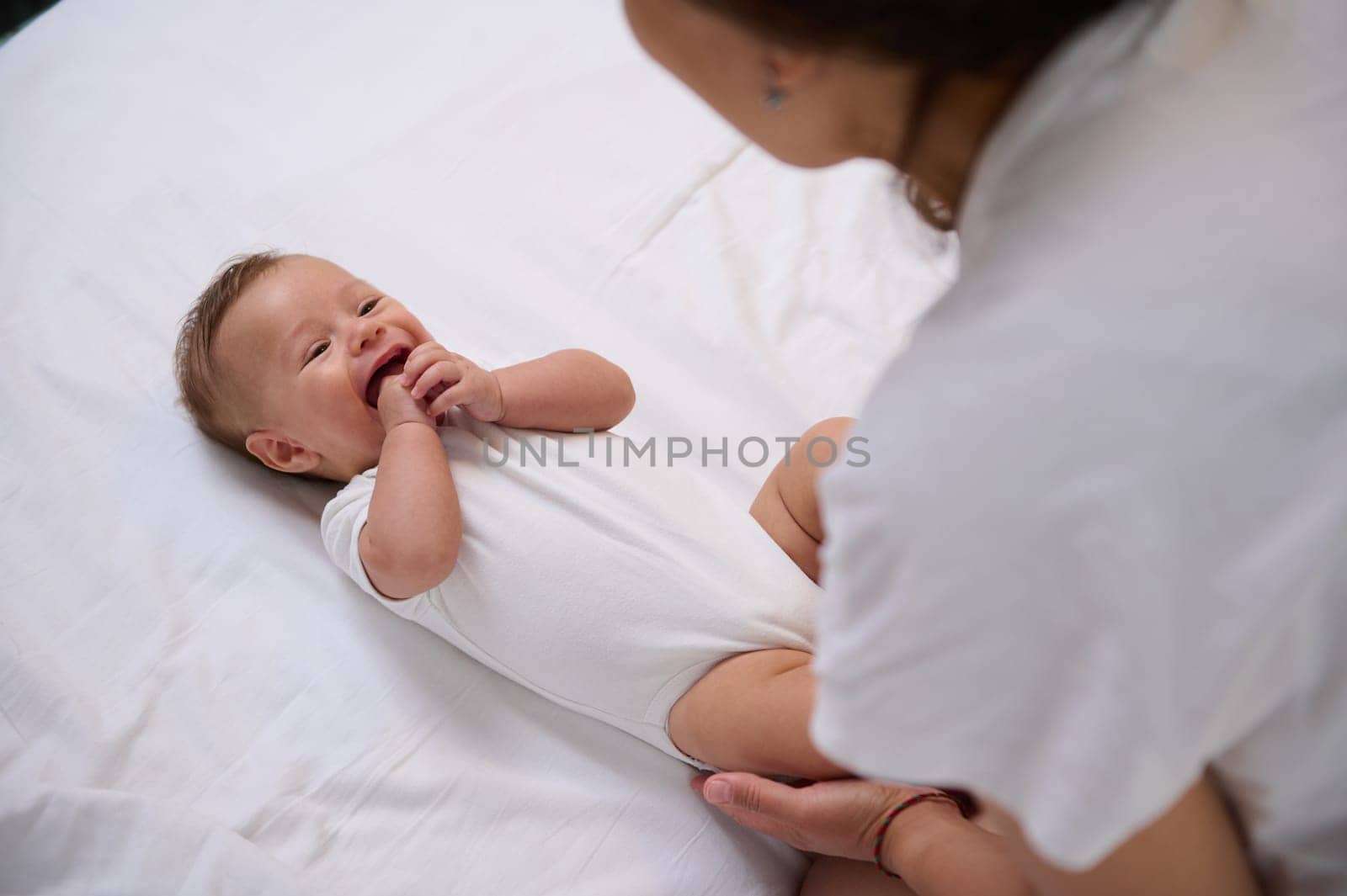Authentic portrait of a mother taking care of her baby boy. Adorable child 4 months old smiling to his mom, feeling emotional connection. Maternity leave and motherhood lifestyle. Babyhood. Infancy
