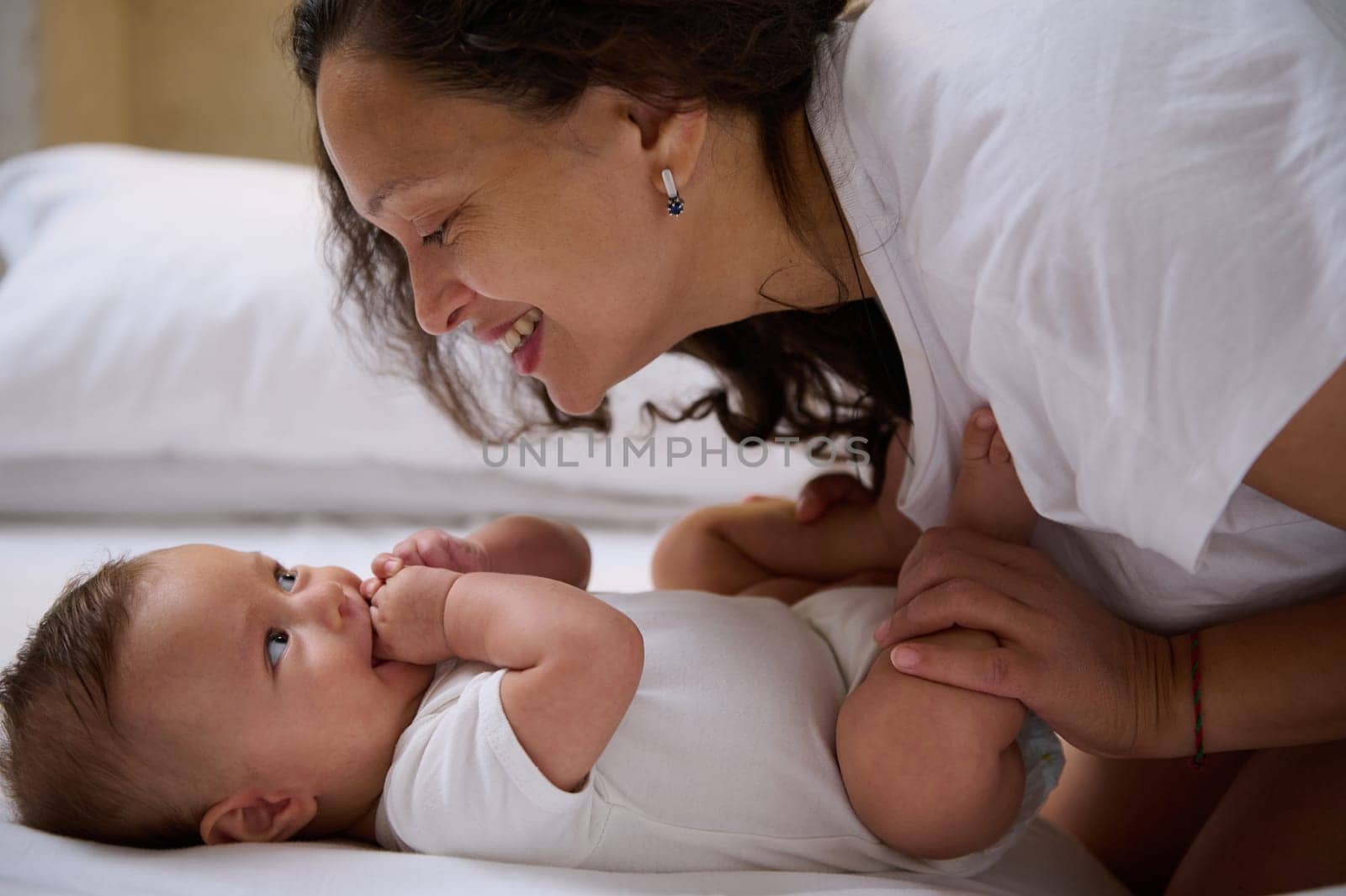 Authentic affectionate loving mother and baby boy son face to face, smiling, enjoying happy moments together. Infancy. Babyhood. Maternity leave concept. Happy family relationships. Smiling baby