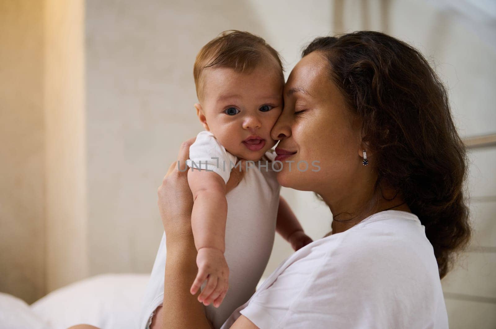 Delightful happy affectionate young mother holding her baby boy 4 months old, smiling and enjoying happy moments with her adorable child, cuddling him. Love. Tenderness. Happy Mother's Day concept