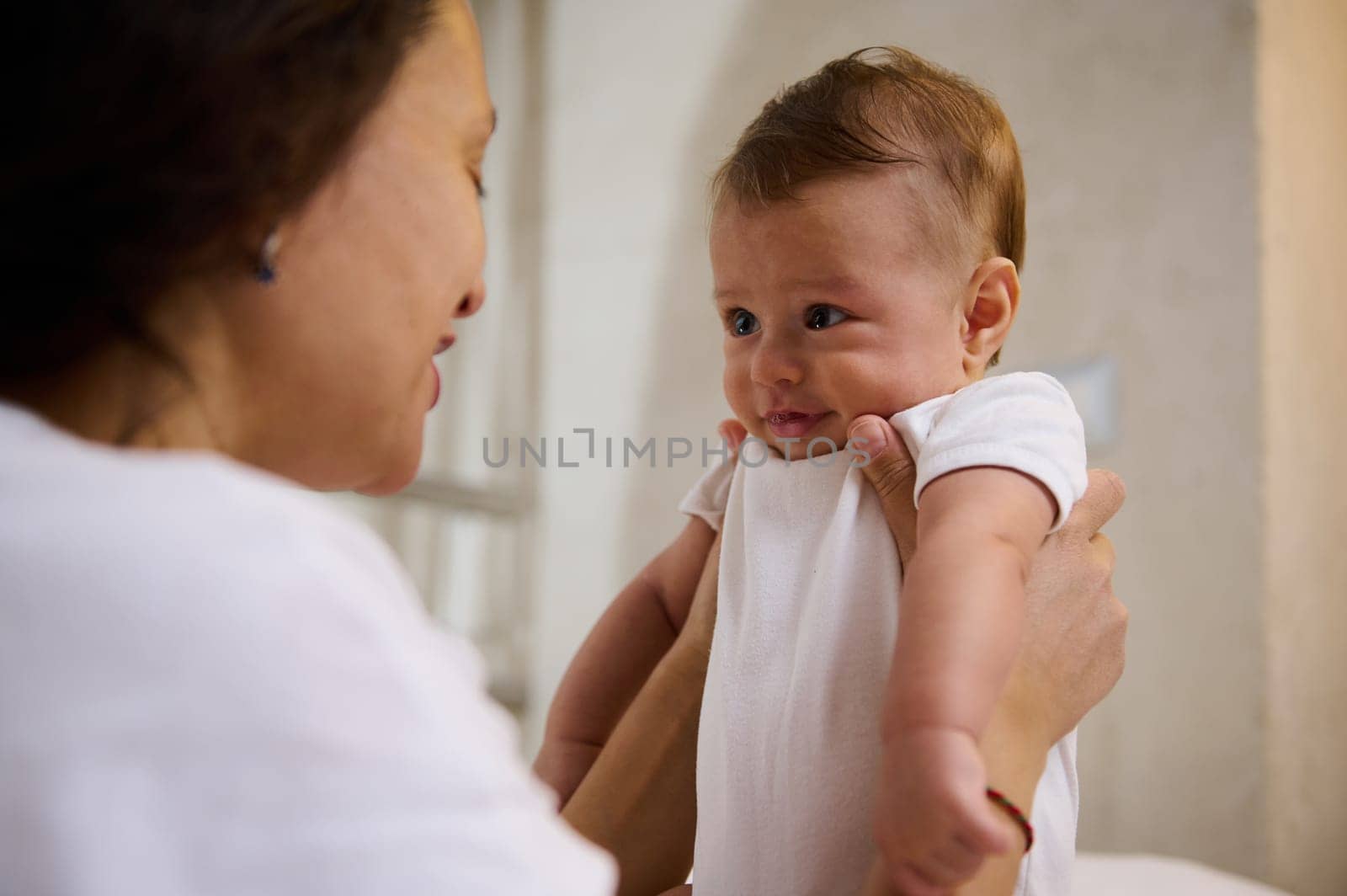 Close-up authentic portrait of adorable baby boy, child of 4 months old smiling to his affectionate loving caring mother holding him in arms. Babyhood and Infancy time. Childbirth Childcare Baby care