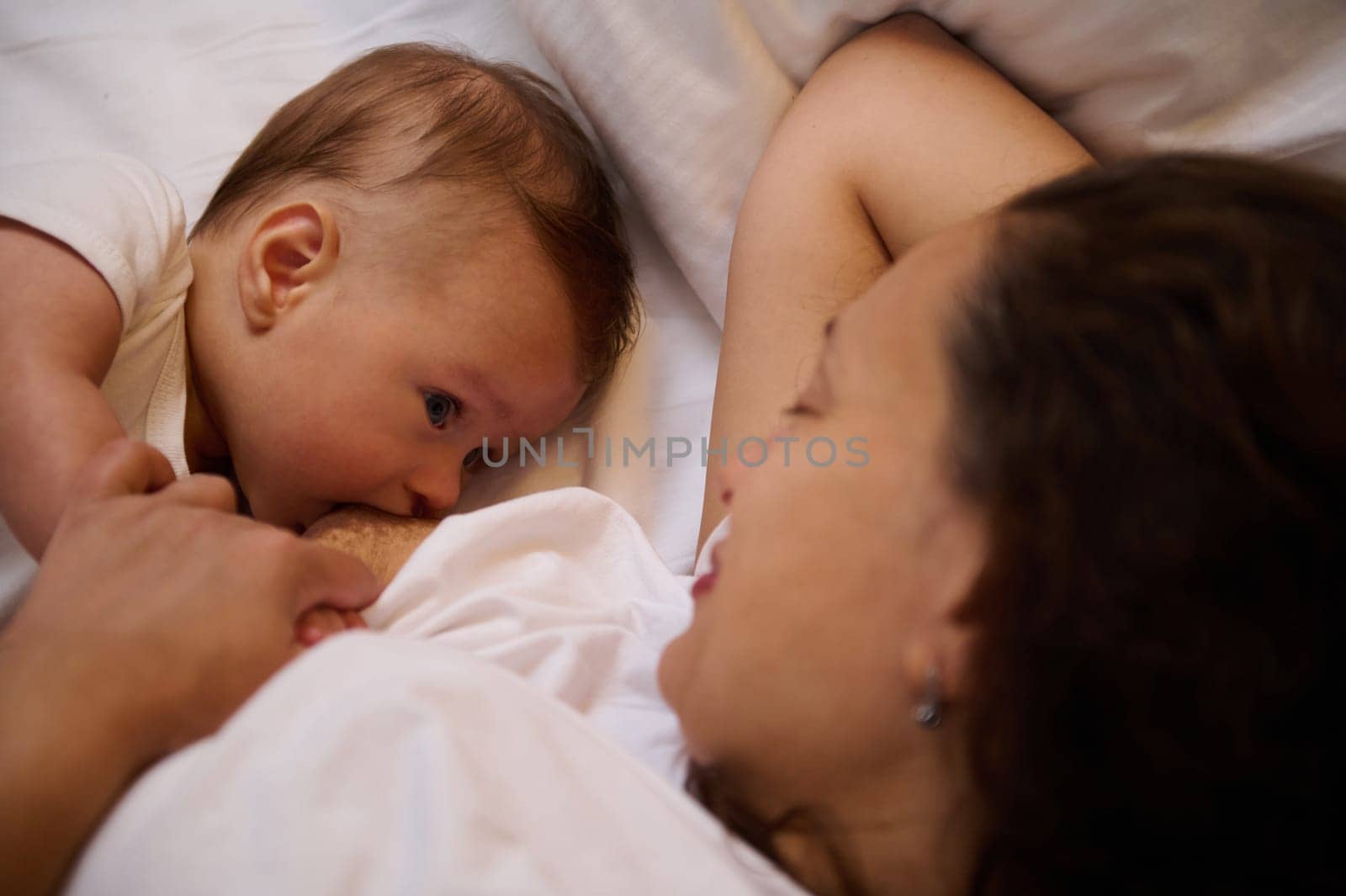Authentic portrait of a newborn baby boy sucking milk from mothers breast. Portrait of mom and breastfeeding baby. Healthy lifestyle. Infancy and maternity concept. Mother's milk - best kids nutrition