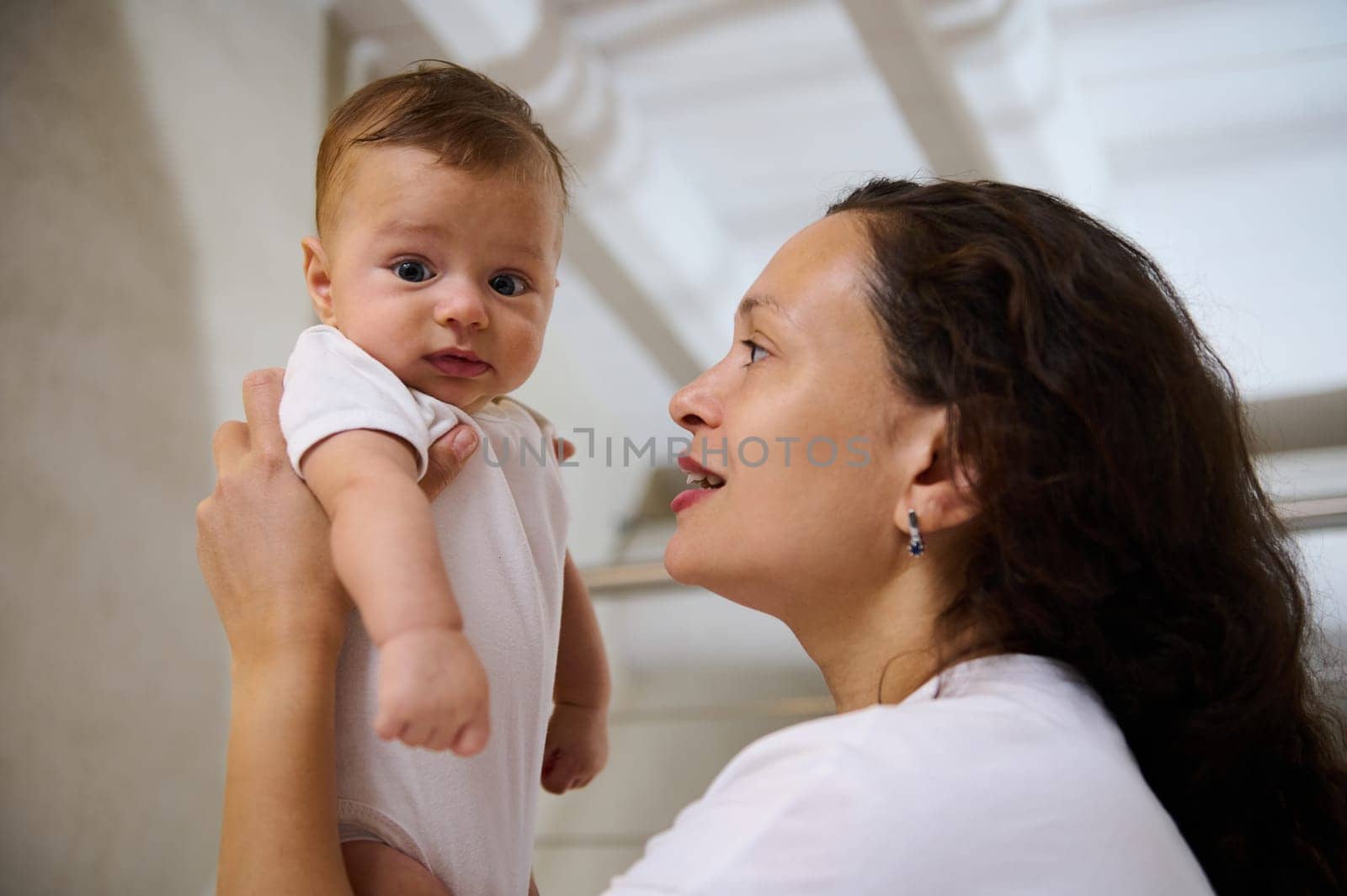 Side view of a happy smiling woman mother holding her baby boy in her arms. Close-up portrait by artgf