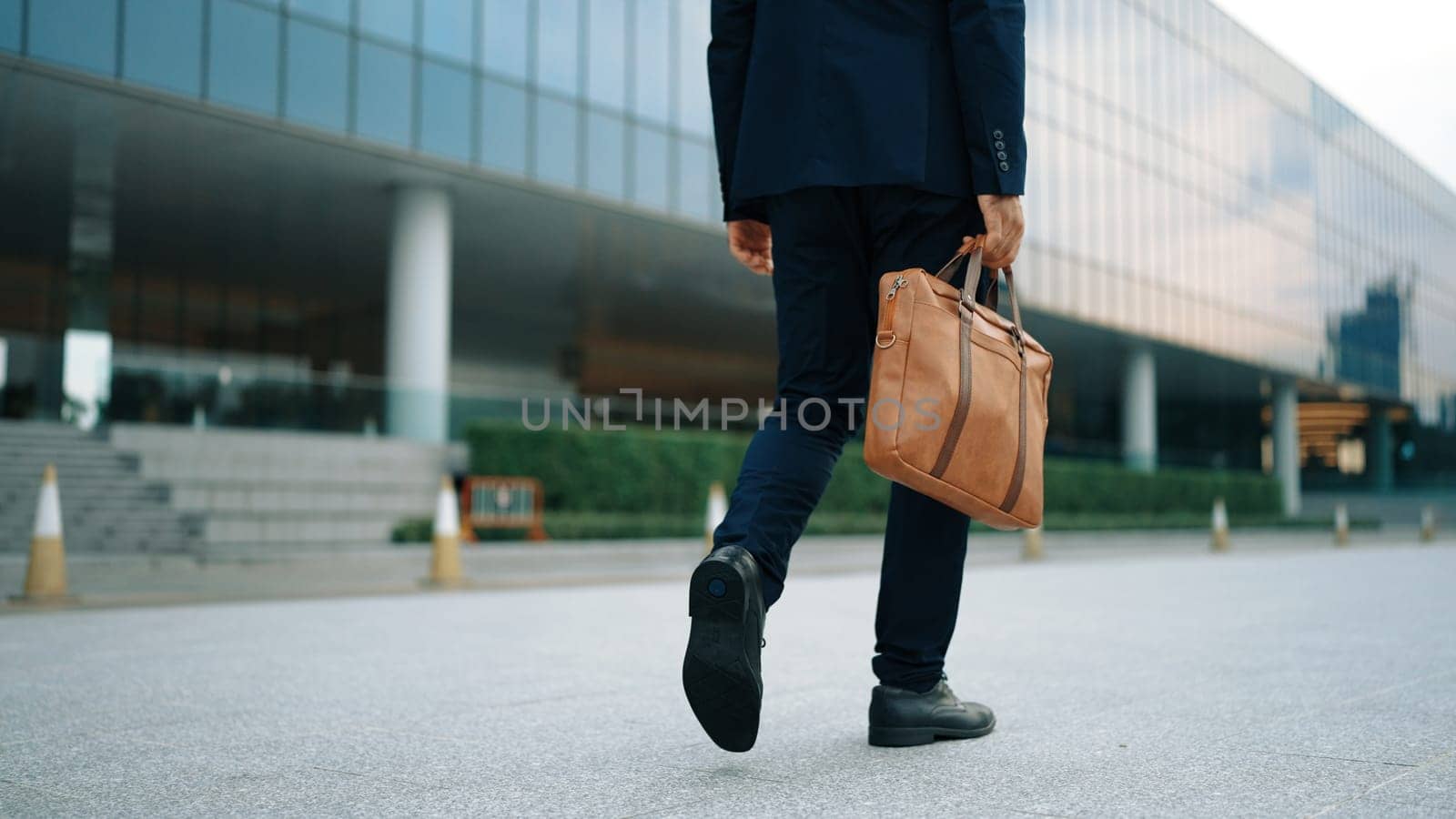 Closeup of business man leg walking while holding bag. Back view. Exultant. by biancoblue
