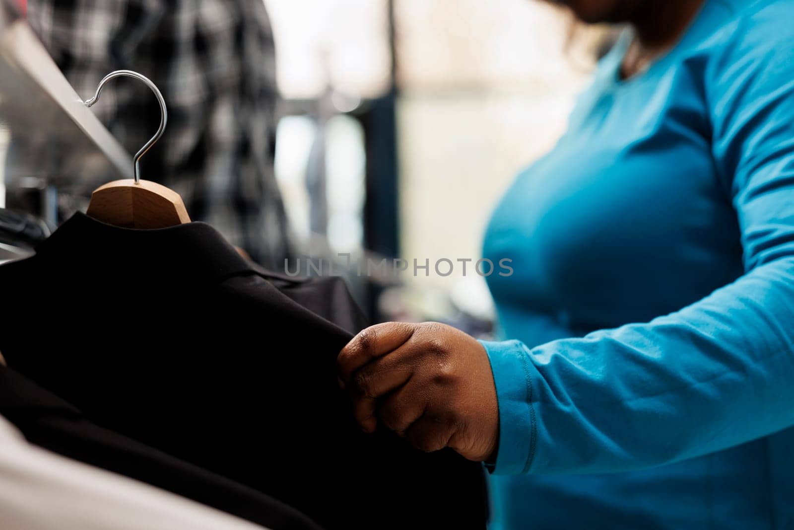 African american shopper looking at trendy suit, shopping for formal wear in modern store. Fashionable client checking clothes fabric before buying it in fashion boutique. Close up