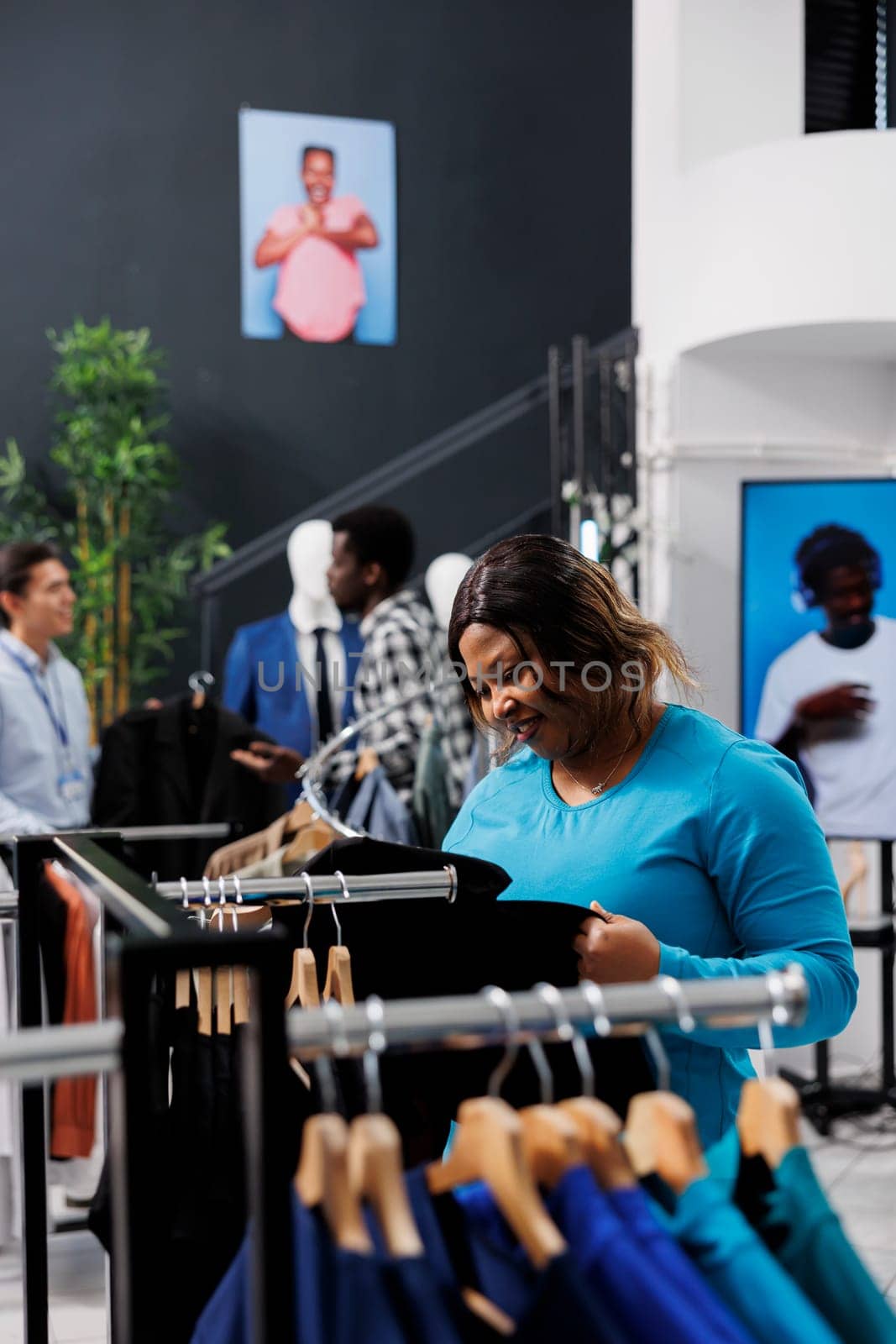 African american shopaholic woman shopping for casual wear in modern boutique, checking merchandise fabric. Stylish customer wanting to buy new fashion collection in clothing store
