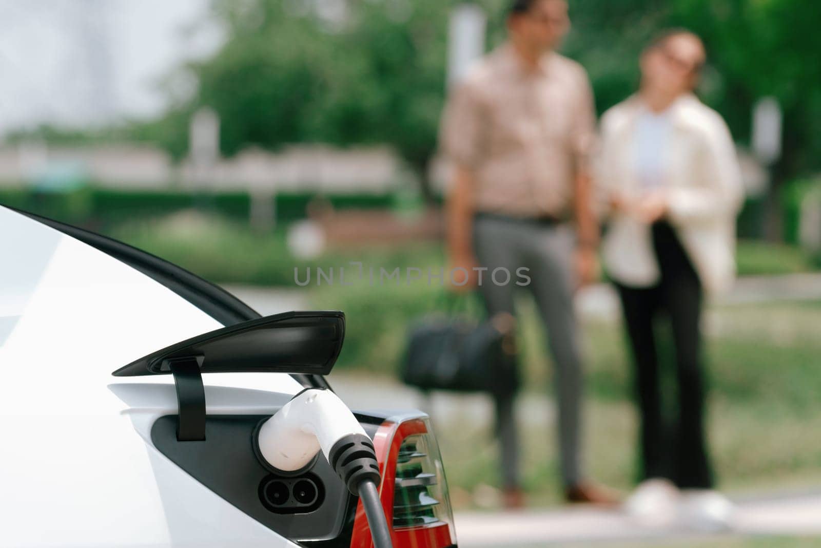 Young couple recharge electric car's battery from charging station. Expedient by biancoblue