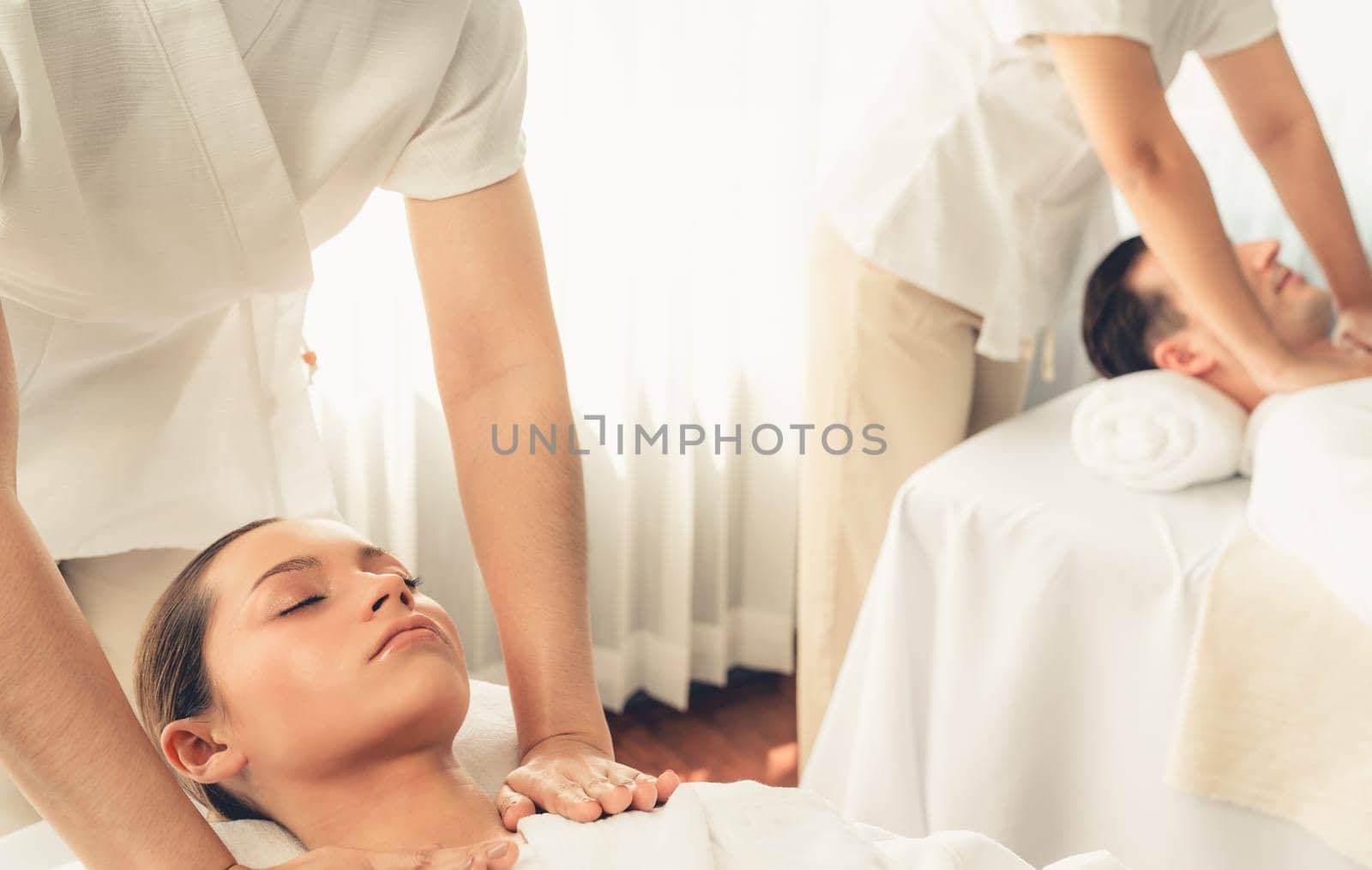 Caucasian couple customer enjoying relaxing anti-stress spa massage and pampering with beauty skin recreation leisure in day light ambient salon spa at luxury resort or hotel. Quiescent