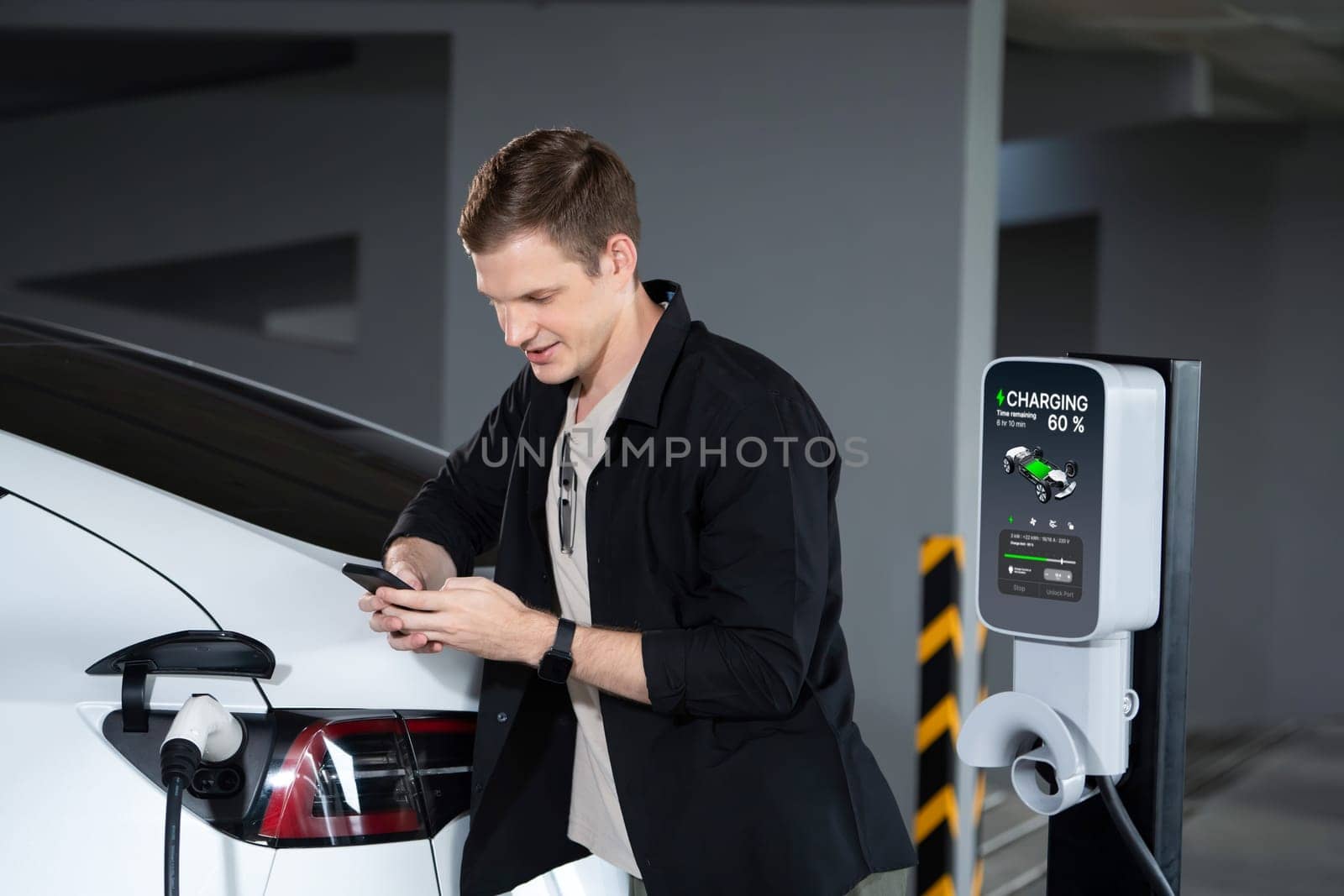 Young man travel with EV electric car to shopping center parking lot charging in downtown city showing urban sustainability lifestyle by green clean rechargeable energy of electric vehicle innards