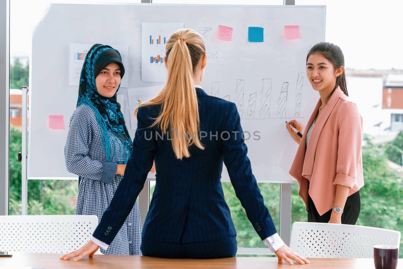 Multicultural working group. Team of businesswomen of different ethnicity, Caucasian, Asian and Arabic working together in team meeting at office. Multiethnic teamwork concept. uds