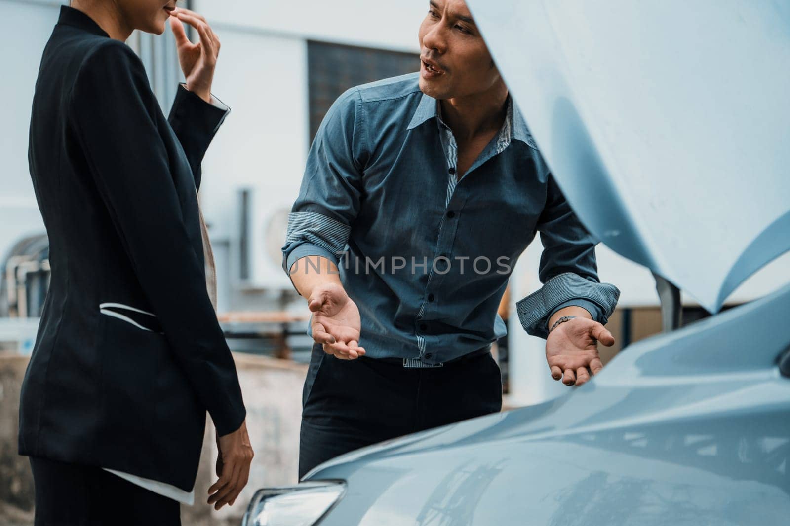 Man help woman fix the car problem. He pop up the car hood to repair the damaged part. uds