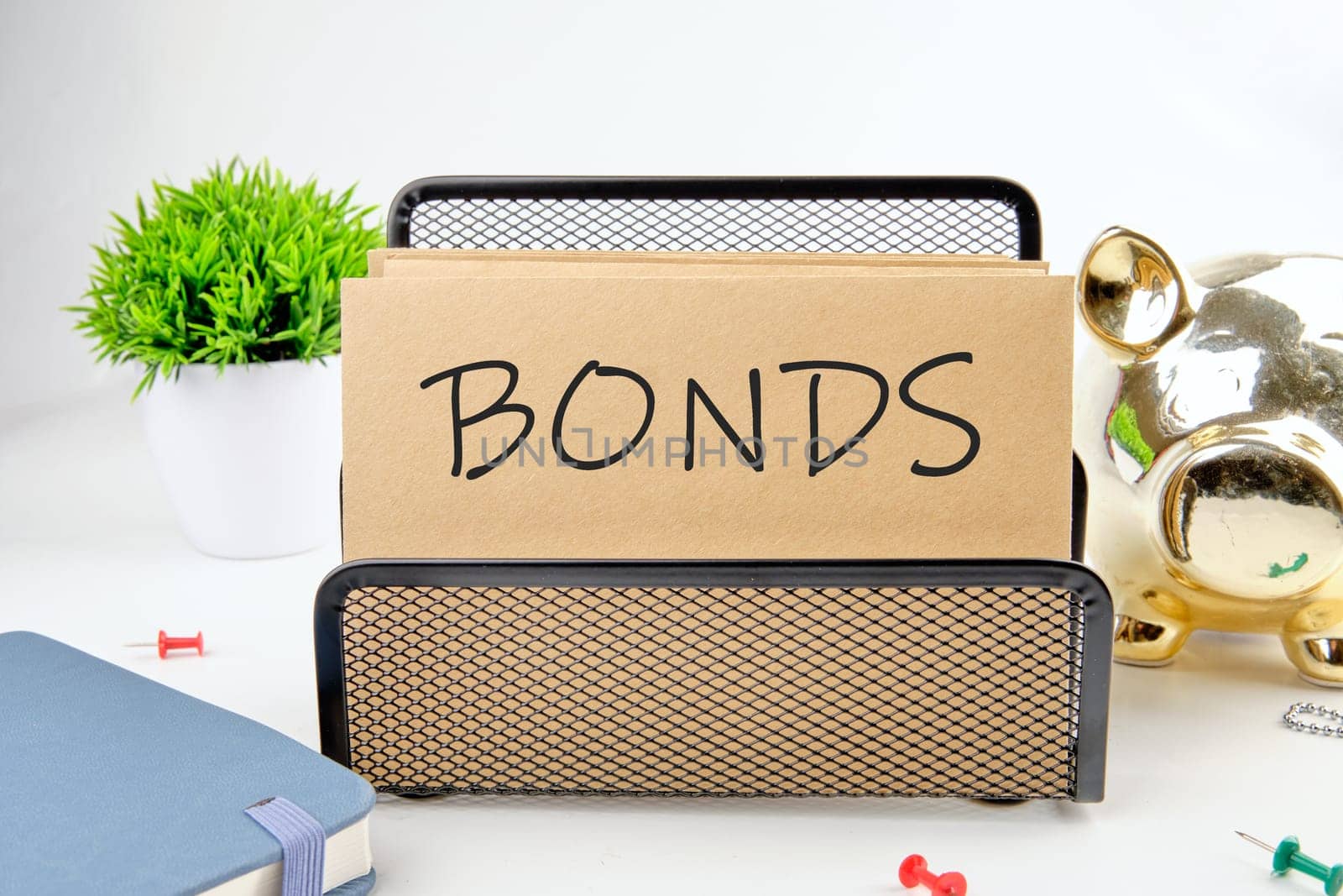 BONDS text on paper next to piggy bank, notepad, flower on a white background