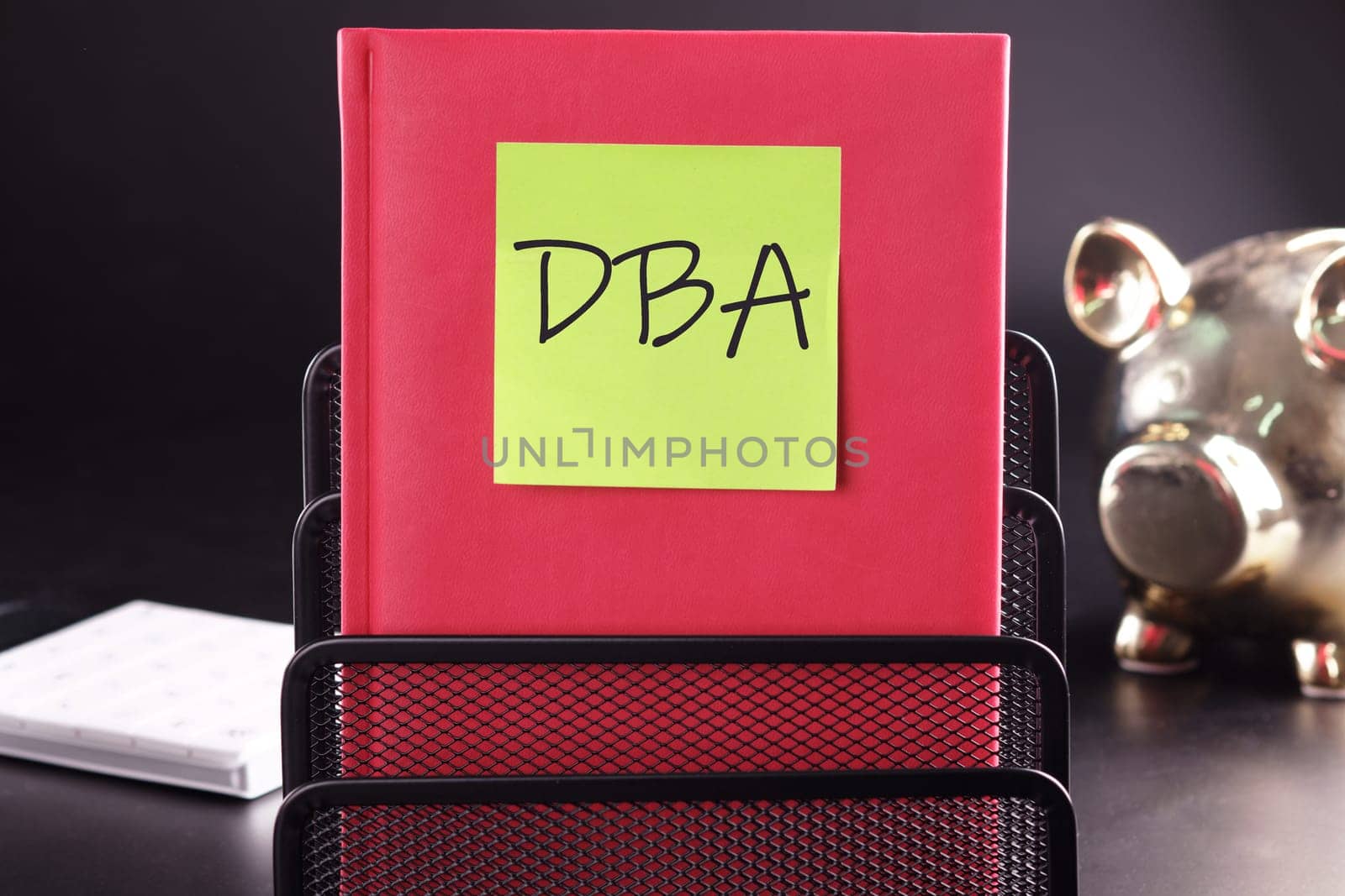 DBA text on a yellow sticker pasted on an upright diary on a black background