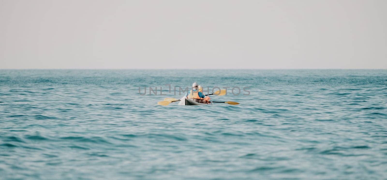 Kayaks. Couple kanoeing in the sea near the island with mountains. People kayaking in the ocean.