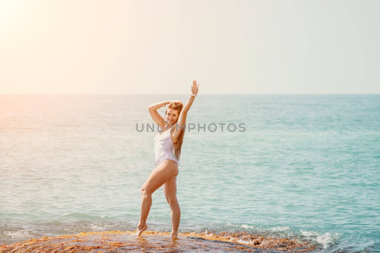 Woman sea yoga. Back view of free calm happy satisfied woman with long hair standing on top rock with yoga position against of sky by the sea. Healthy lifestyle outdoors in nature, fitness concept by panophotograph