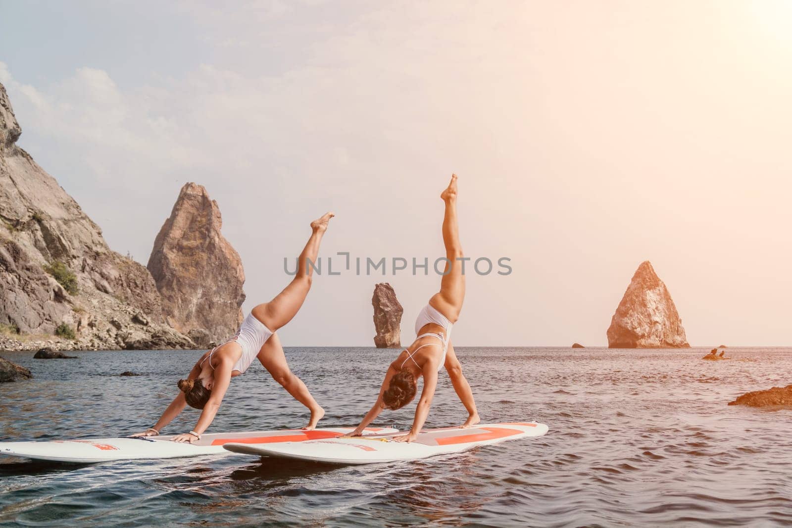 Woman sup yoga. Happy sporty woman practising yoga pilates on paddle sup surfboard. Female stretching doing workout on sea water. Modern individual female hipster outdoor summer sport activity. by panophotograph