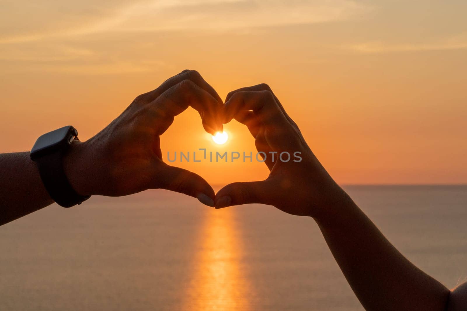 Hands heart sea sanset. Hands forming a heart shape made against the sun sky of a sunrise or sunset on a beach.