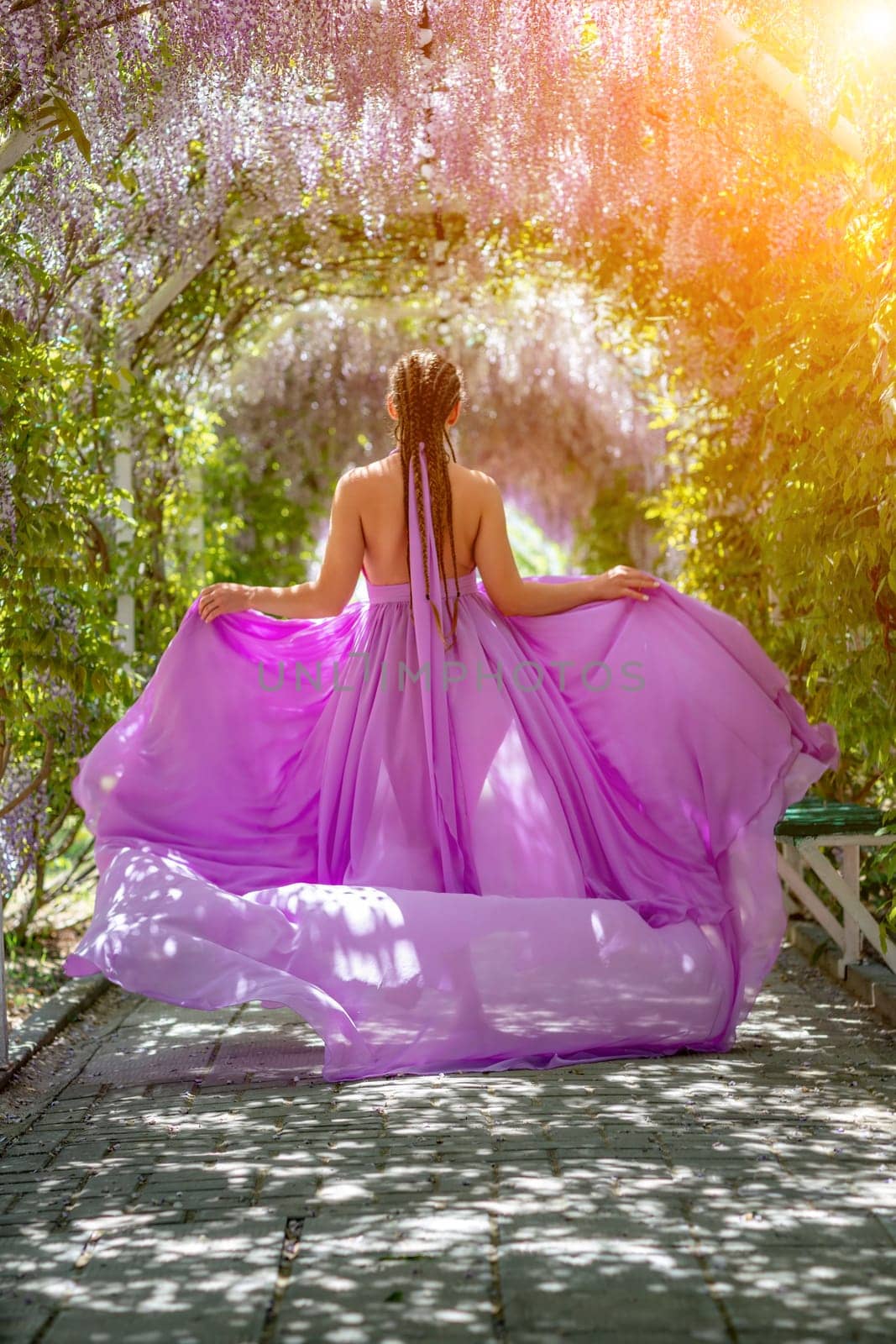 Woman wisteria lilac dress. Thoughtful happy mature woman in purple dress surrounded by chinese wisteria by Matiunina