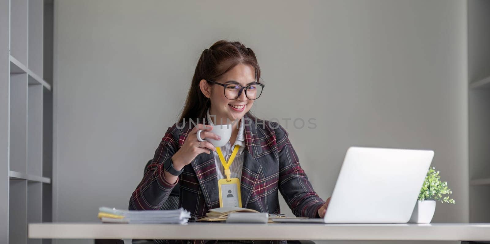 Young businesswoman sitting and exploring work data while having a cup of coffee to relax..