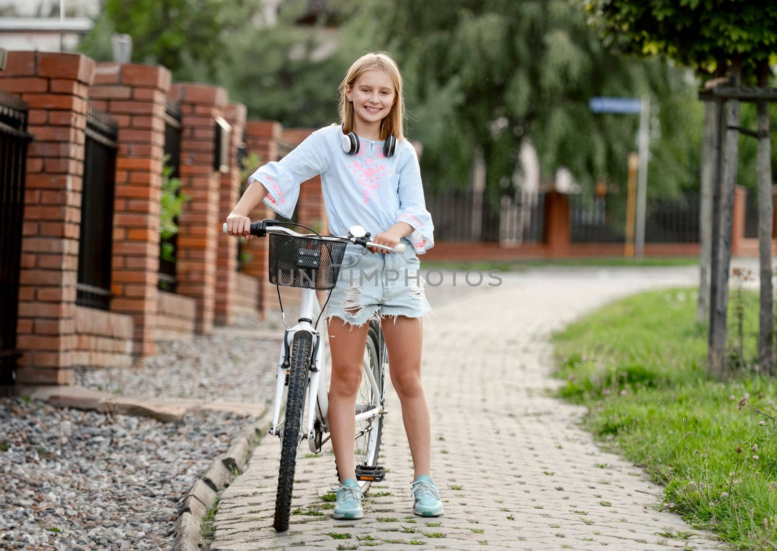 Cute preteen girl with bycicle outdoors looking at camera and smiling. Pretty child with bike at city street