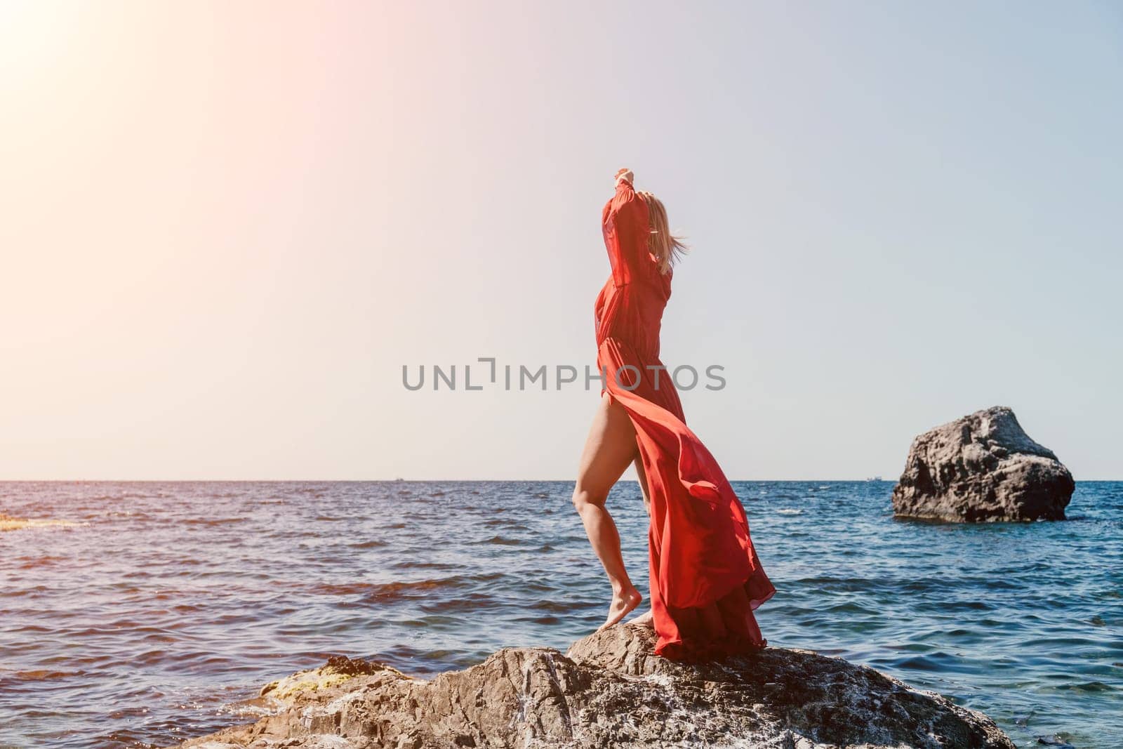 Woman travel sea. Happy tourist in long red dress enjoy taking picture outdoors for memories. Woman traveler posing on beach at sea surrounded by volcanic mountains, sharing travel adventure journey by panophotograph