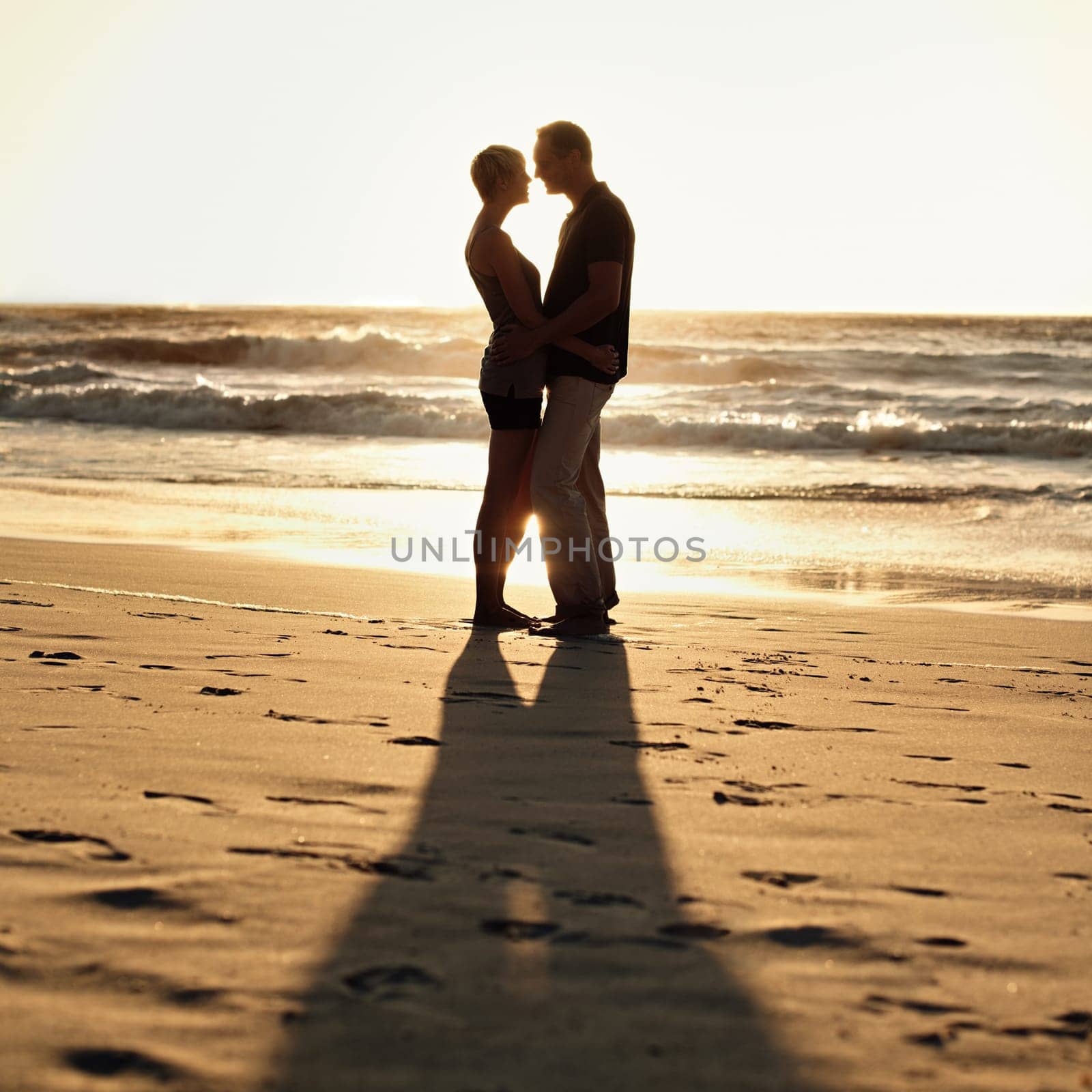 Silhouette, couple and kiss on beach at sunset for romantic, date and weekend getaway in Turkey. Woman, man or people in love with hug for walk, bonding or together in caring happy relationship.