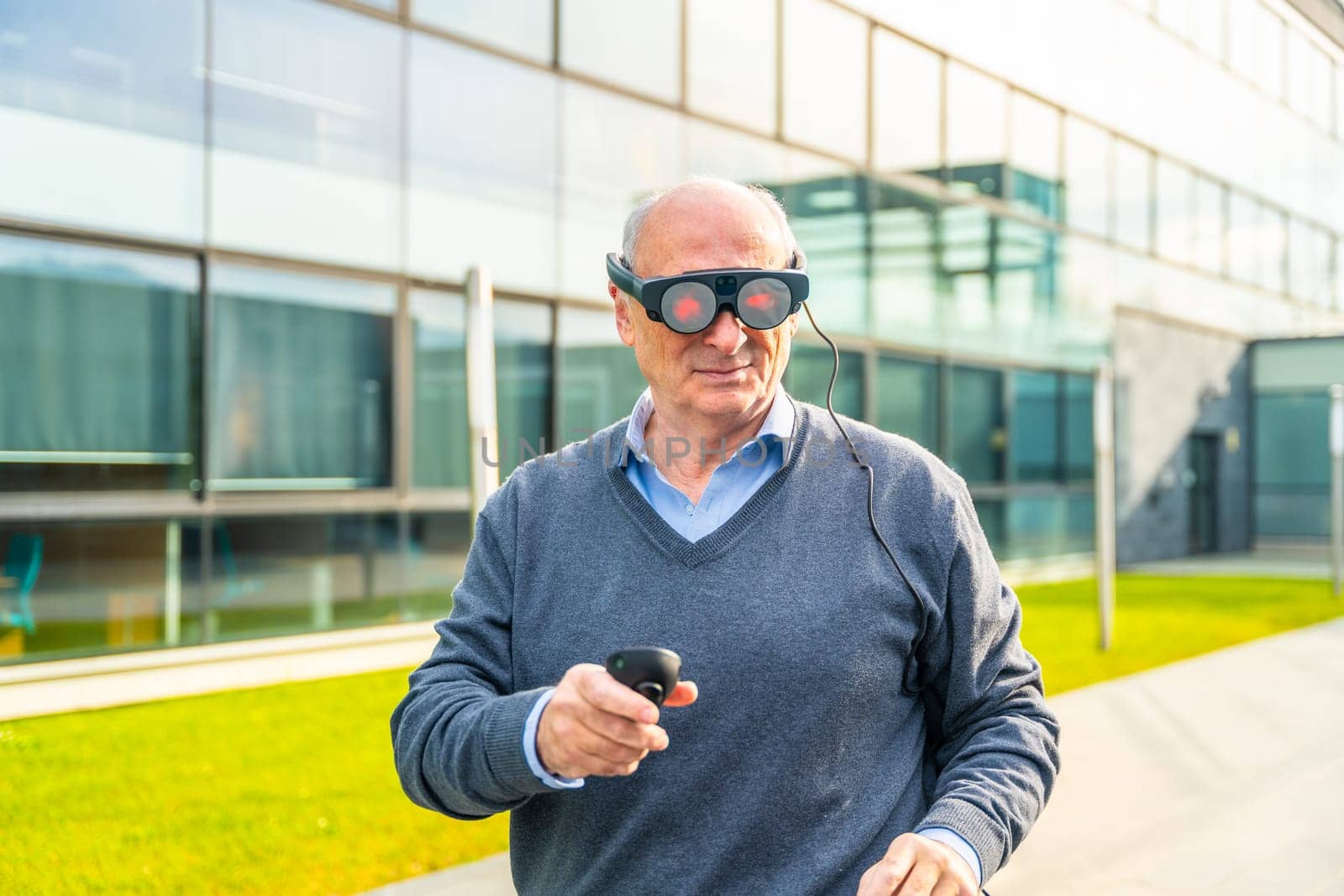 Smiling elder businessman using an augmented reality device outside the financial building