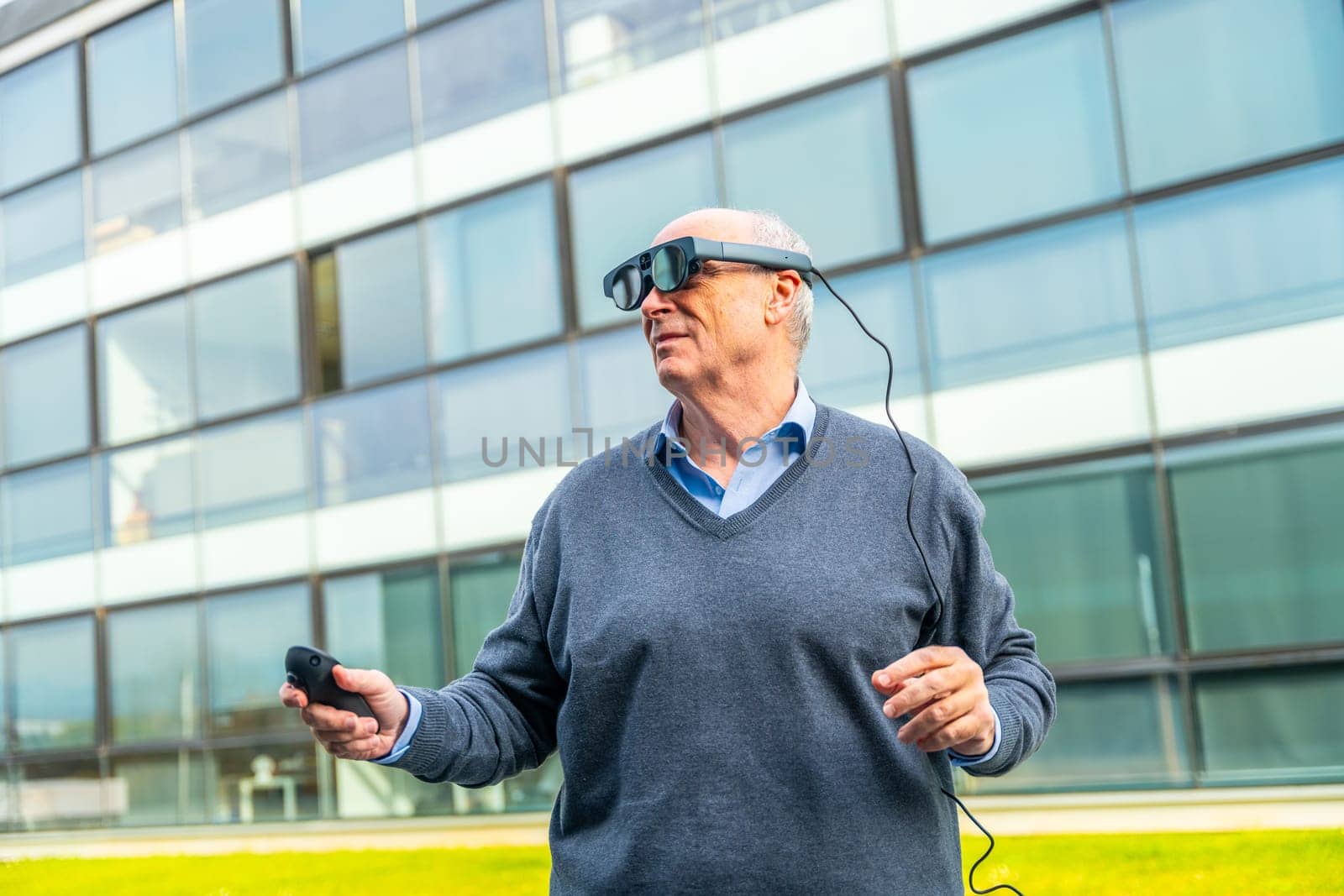 Horizontal photo with copy space of an aged man interacting with augmented vision goggles outside the office