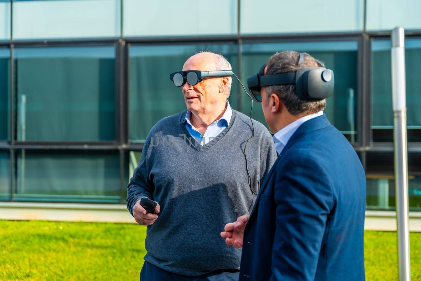 Aged businessmen testing virtual reality headset outdoors by Huizi
