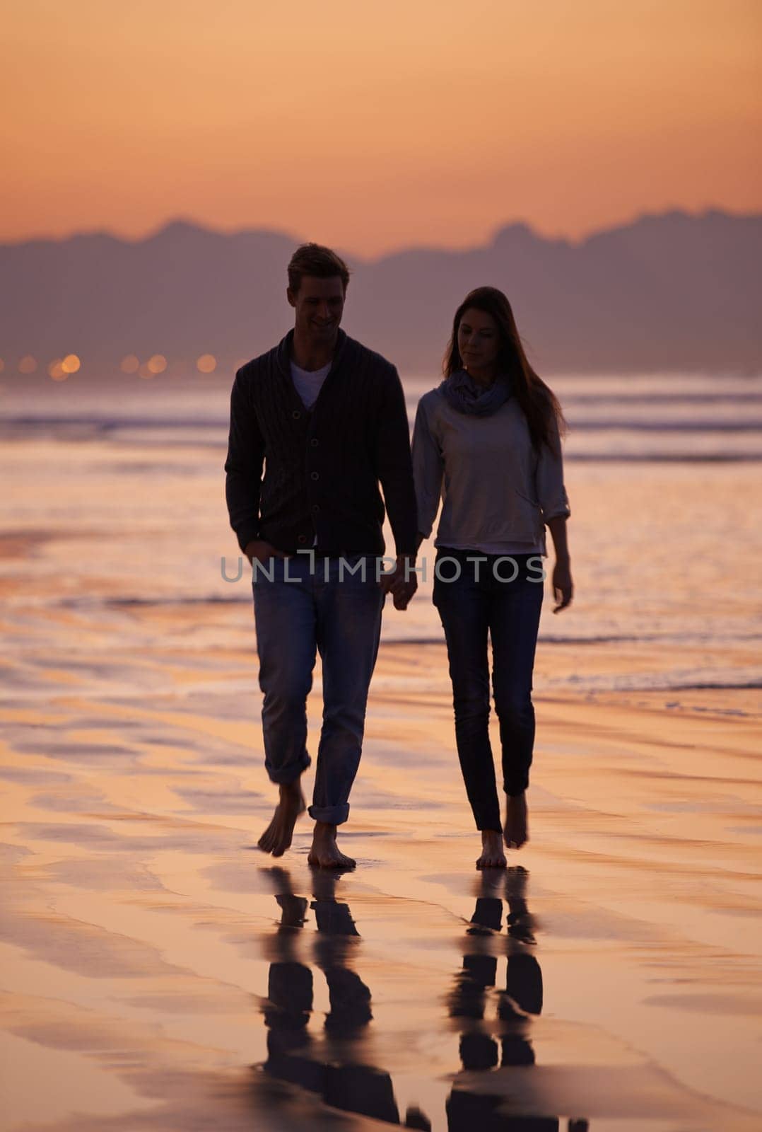 Couple, holding hands and walking on beach for sunset, nature and travel with bonding for love and commitment outdoor. People, trust and loyalty with adventure together for honeymoon or anniversary.