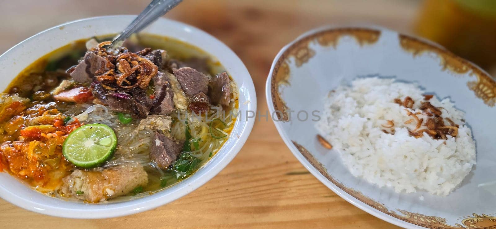 Indonesian style beef noodle soup called soto mie, freshly made soup with vermicelli rice noodle, fried shallots, chilli paste, and fried rissoles and fresh lime juice