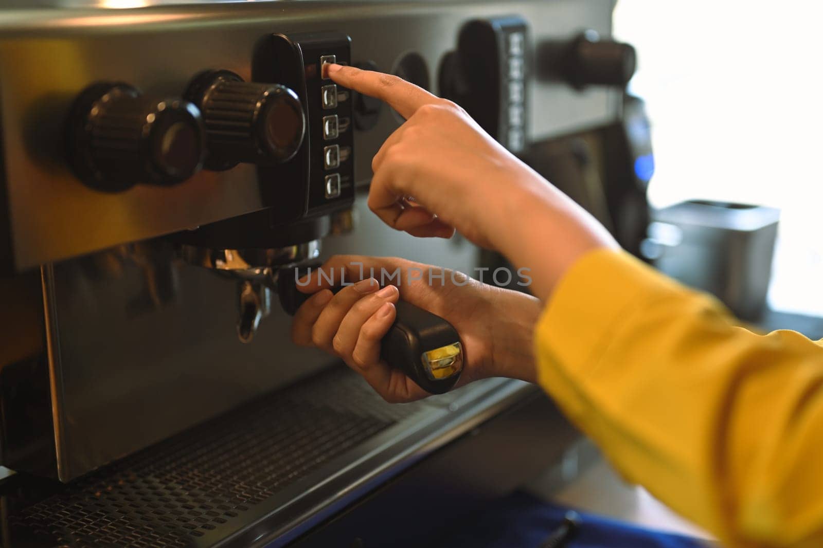 Close up barista using modern coffee machine, preparing coffee for customer in cafe by prathanchorruangsak