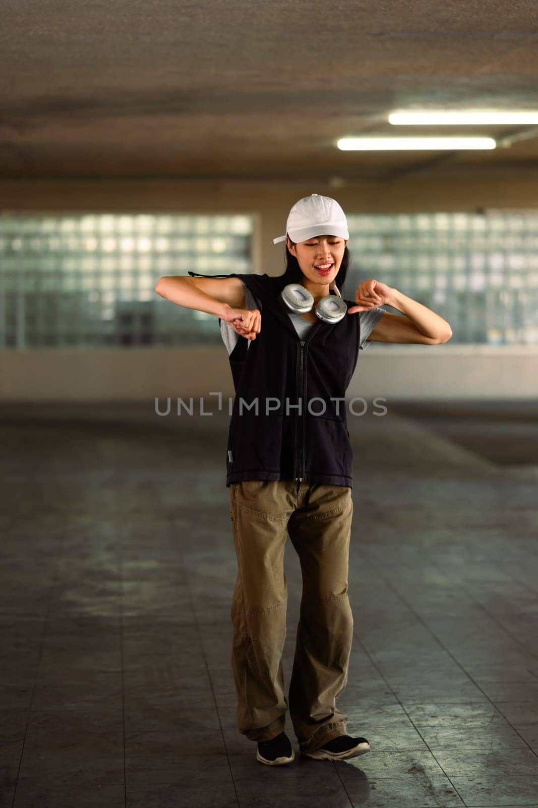 Smiling young female dancing in parking garage. Hobby and active lifestyle concept by prathanchorruangsak