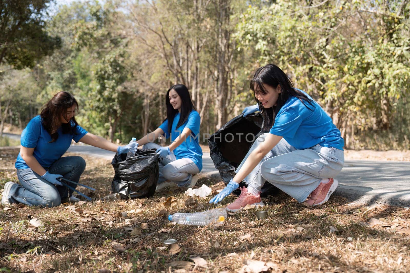 Young people friend volunteer collecting garbage plastic bottles to trash bags. environmental care ecology concept.