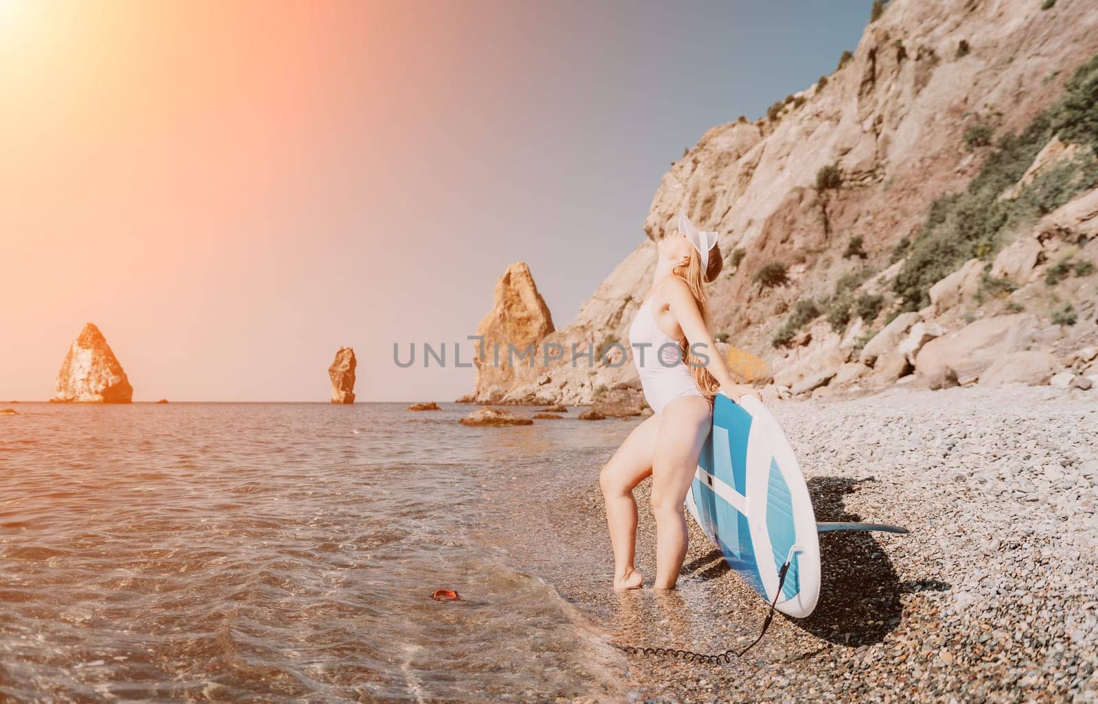 Woman sea sup. Close up portrait of happy young caucasian woman with long hair looking at camera and smiling. Cute woman portrait in a white bikini posing on sup board in the sea by panophotograph