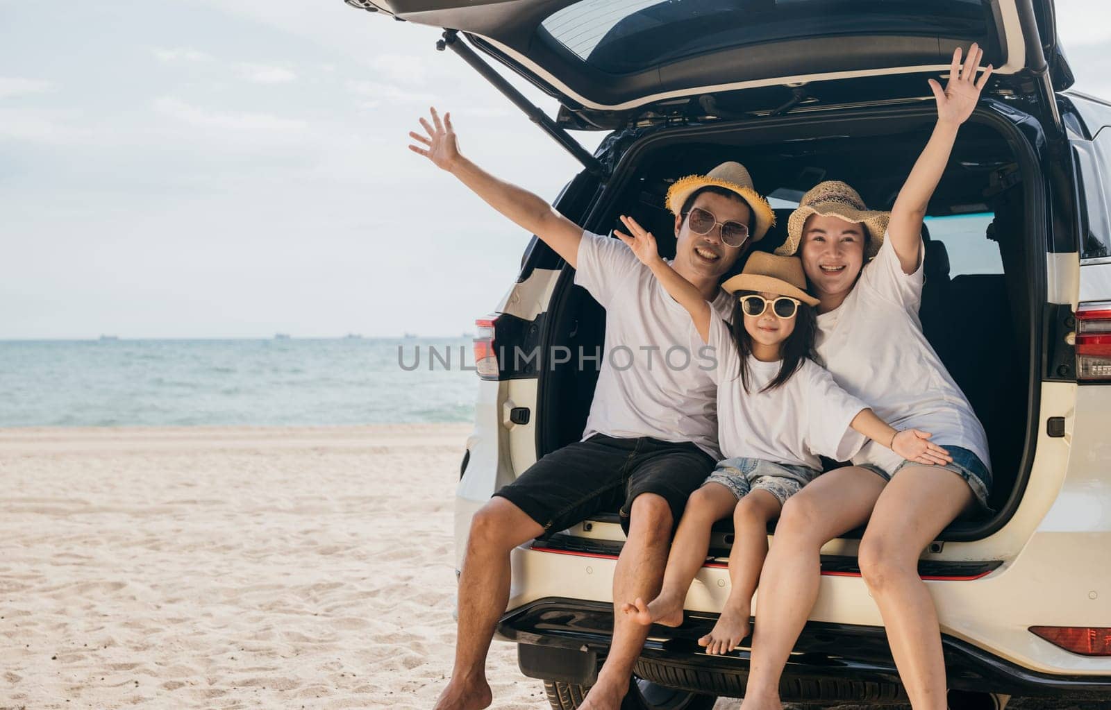 Family Day. Happy people having fun in summer vacation on beach, Family traveling in holiday at sea beach, Dad, mom and children daughter enjoying road trip sitting on family back car raise hand up