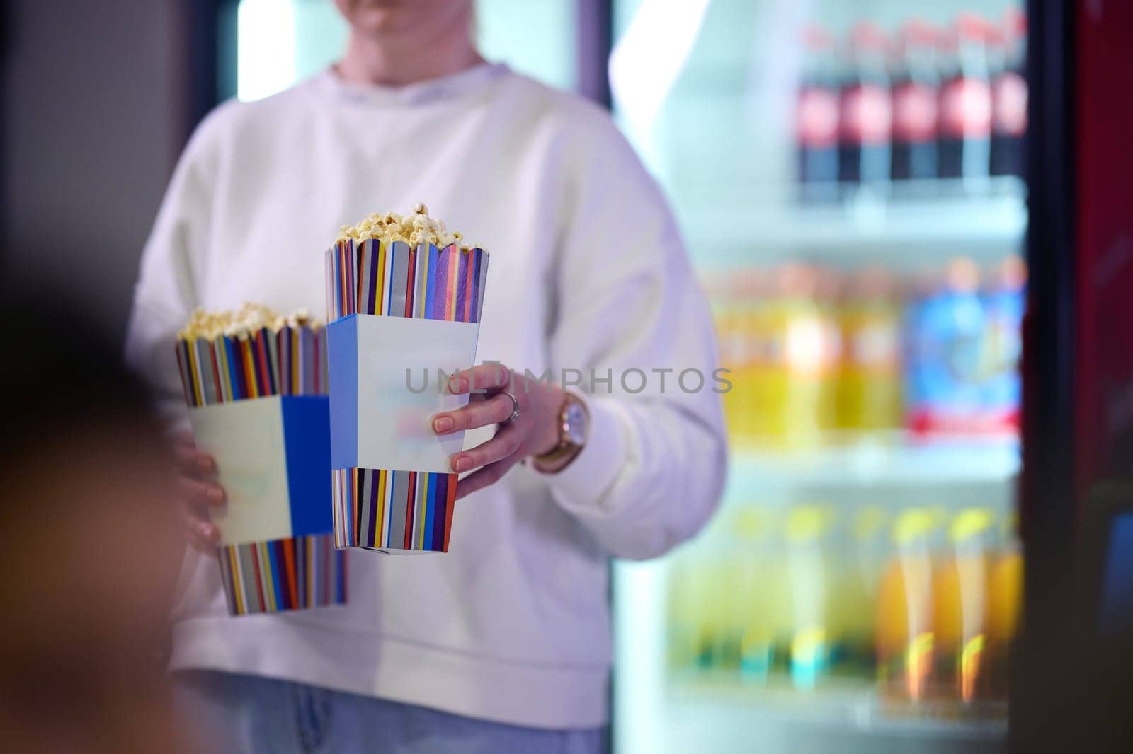 A vendor stands outside the cinema, holding freshly popped popcorn to sell to moviegoers before they enter the theater.