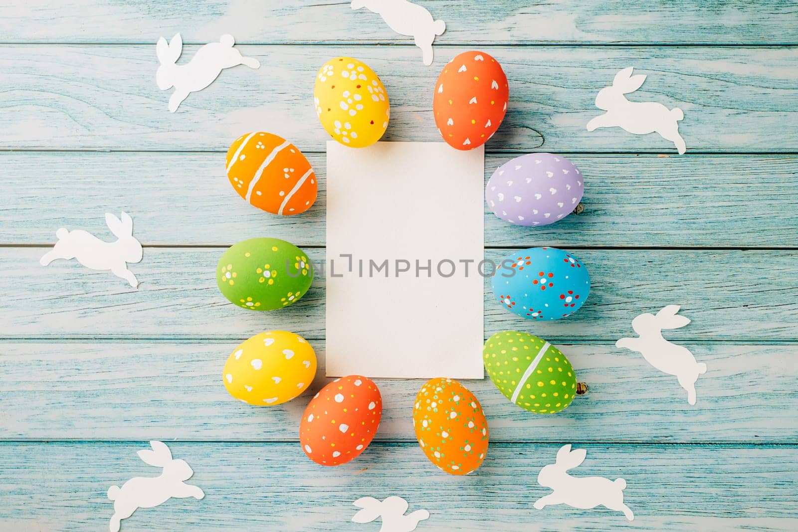 Easter Day Concept. Flat lay holiday banner background web design white colorful easter eggs composition with paper rectangle blank on blue wood background with empty copy space, celebration greeting