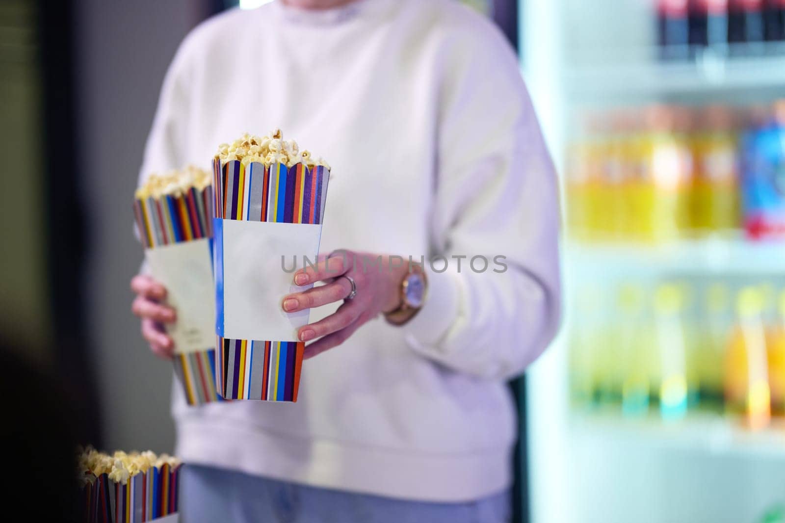 A vendor stands outside the cinema, holding freshly popped popcorn to sell to moviegoers before they enter the theater.