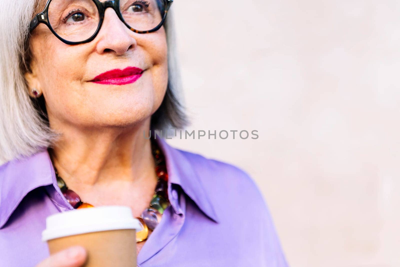 close up portrait of a smiling senior woman holding a takeaway coffee in her hand, concept of elderly people leisure and active lifestyle, copy space for text