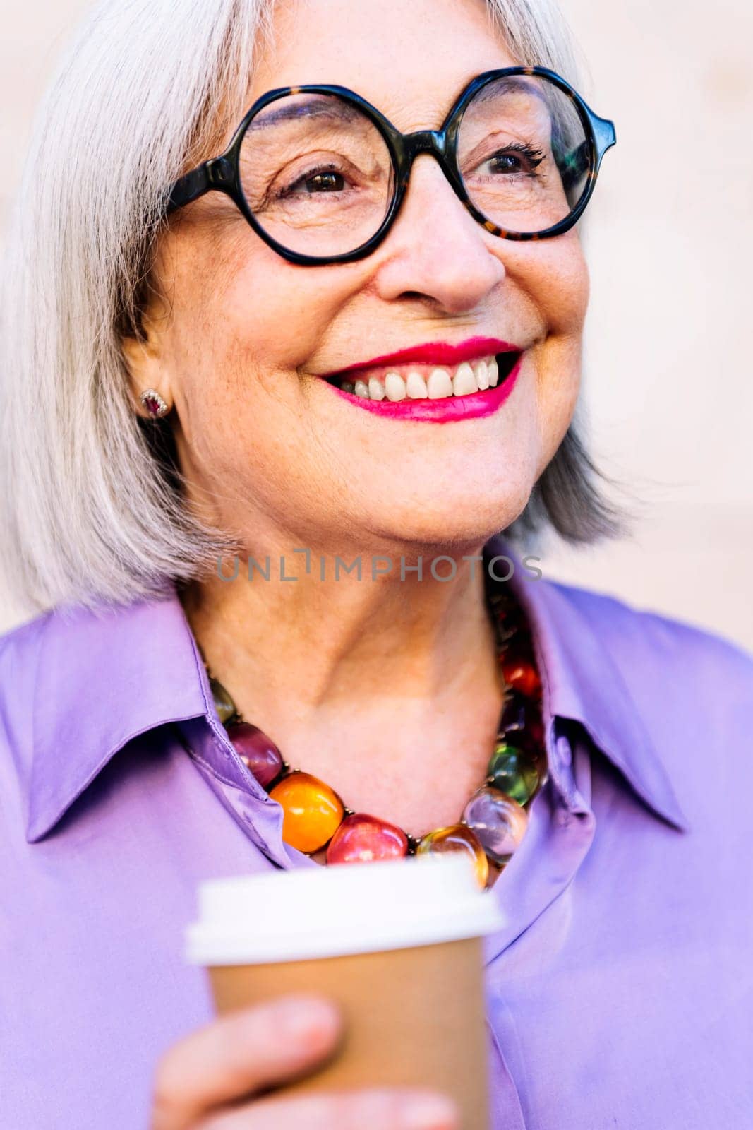 close up portrait of a smiling senior woman holding a takeaway coffee in her hand, concept of elderly people leisure and active lifestyle