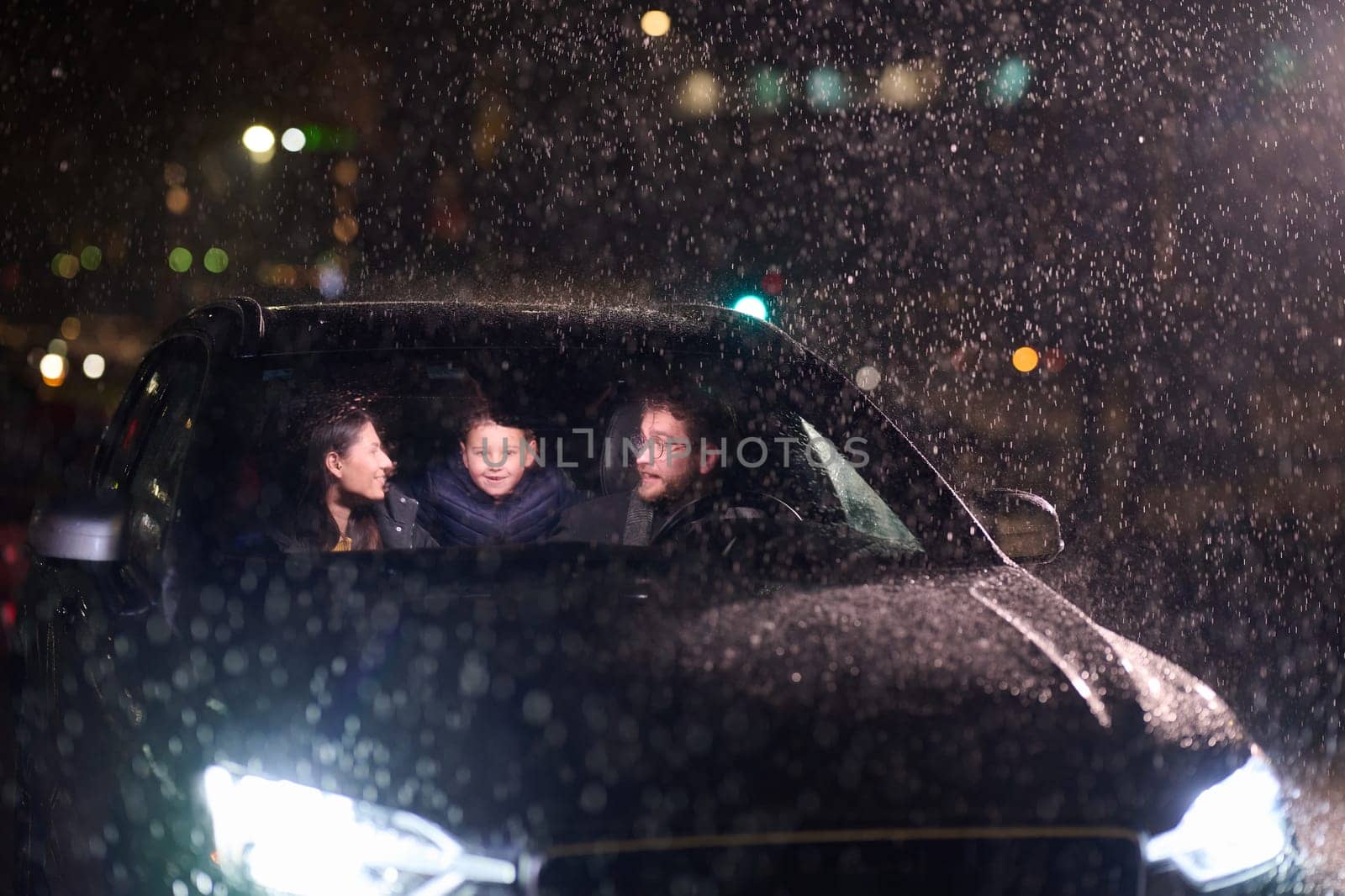 In the midst of a nighttime journey, a happy family enjoys playful moments inside a car as they travel through rainy weather, illuminated by the glow of headlights, laughter, and bonding by dotshock