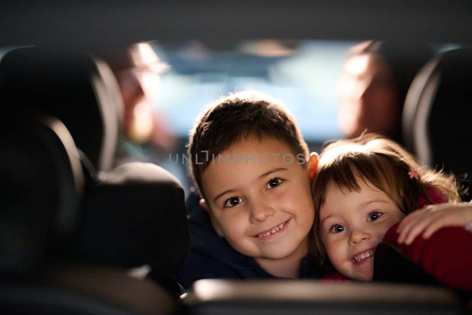 A young brother and sister enjoying a car ride together, immersed in the adventure of travel.