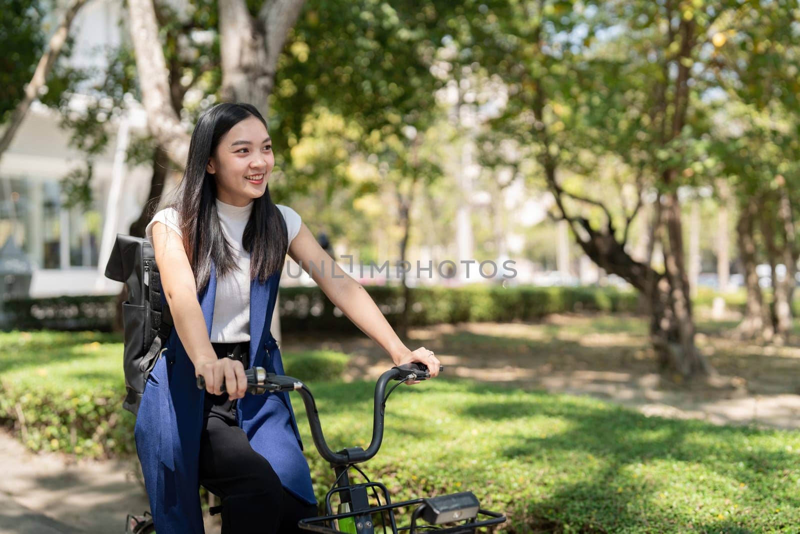 Asian businesswoman in bicycle go to work at office. Bike commuting, happy businesswoman using eco transport, Concept of eco lifestyle by nateemee