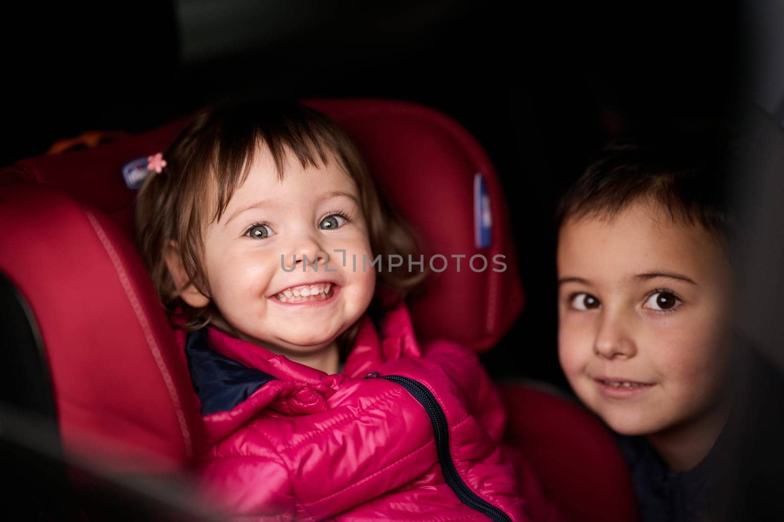 A young brother and sister enjoying a car ride together, immersed in the adventure of travel.