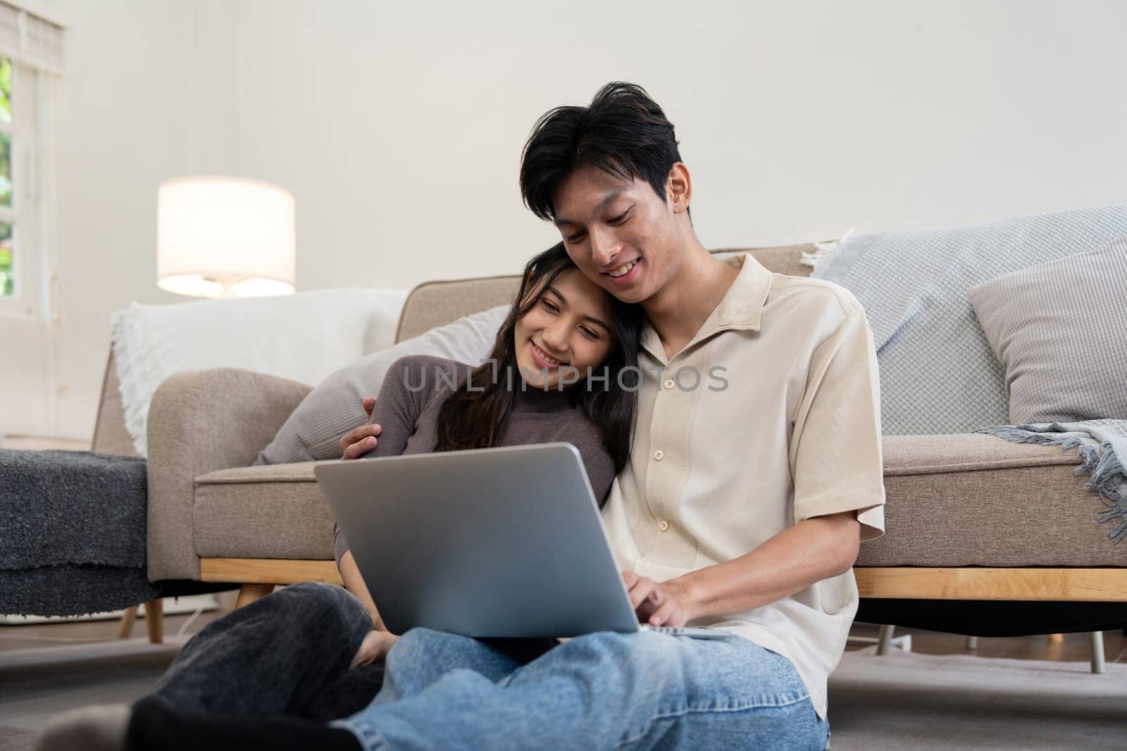 Happy couple asian with laptop on floor in the living room at home by nateemee
