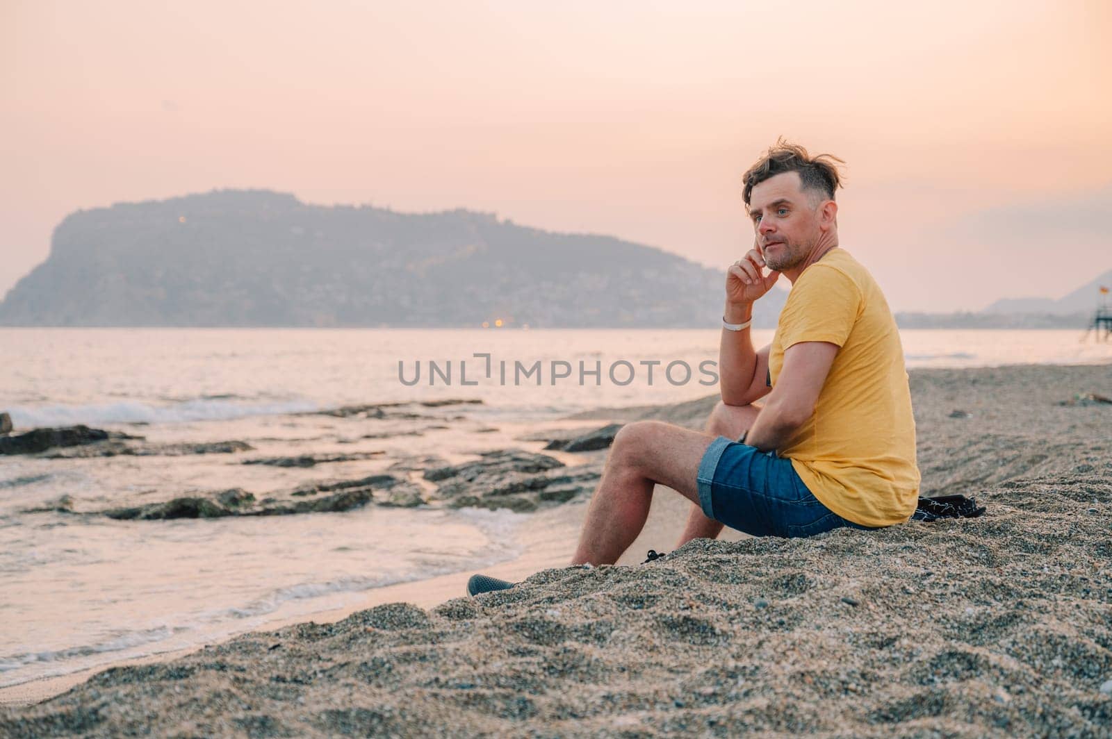 Man sits on the beach and looks at the sea in Alanya city, Turkey. Travelling or vacation concept