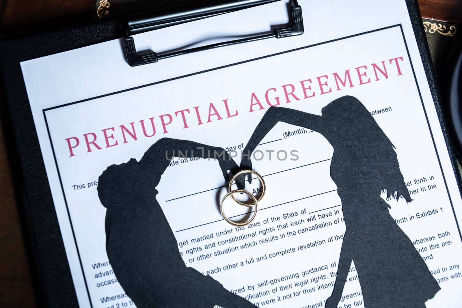 A prenuptial agreement with a silhouette of a couple and wedding rings, symbolizing marital contracts and legal preparation. by jbruiz78