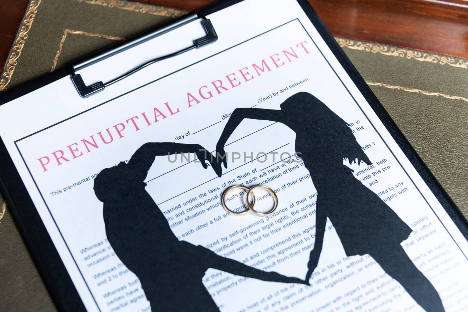 A prenuptial agreement with a silhouette of a couple and wedding rings, symbolizing marital contracts and legal preparation. by jbruiz78