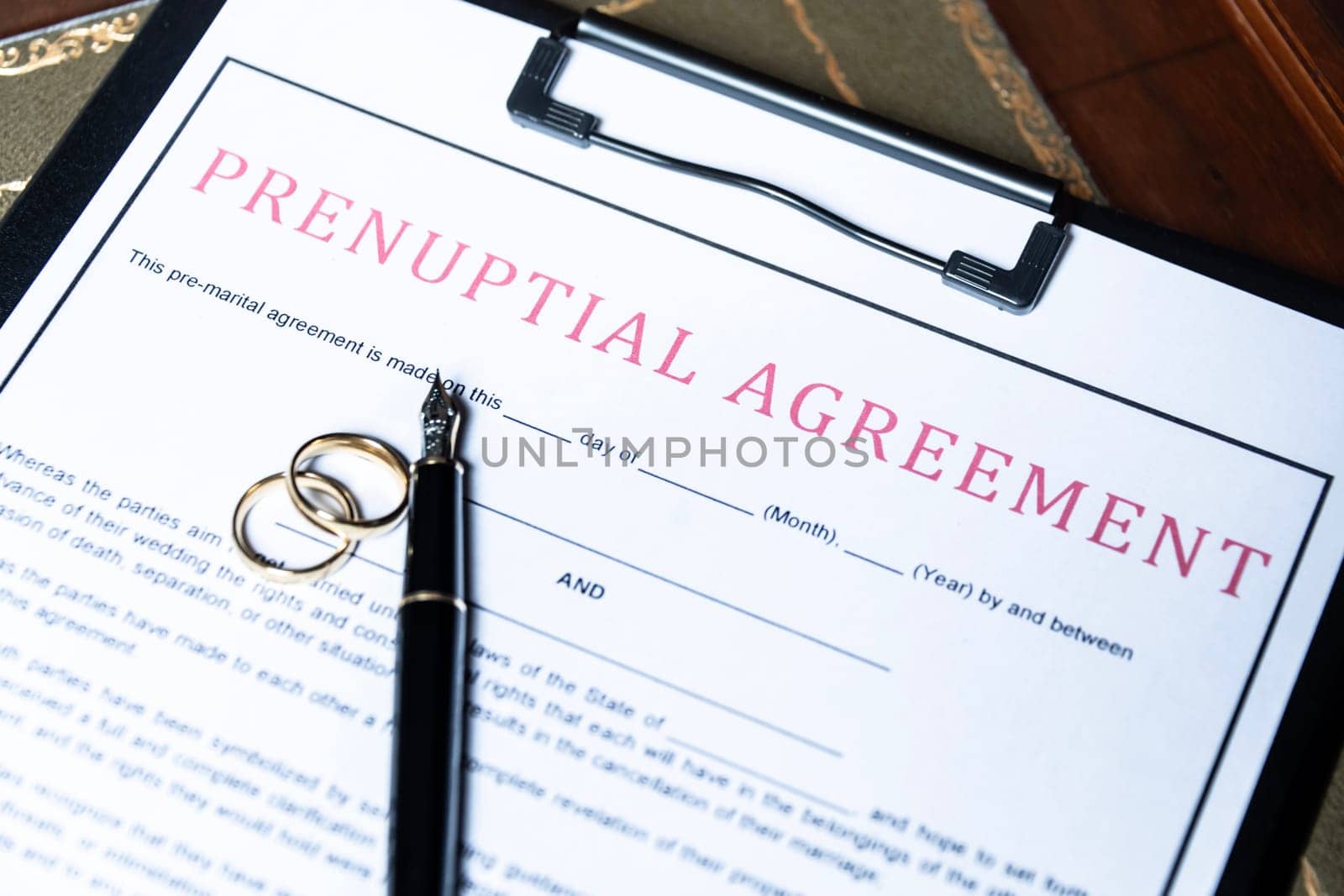 Close-up of a prenuptial agreement form with wedding rings and a fountain pen, indicating the legal aspects of marriage preparation. by jbruiz78